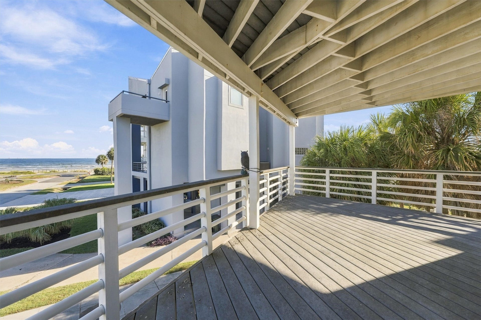 4207 Barataria Court, Galveston, TX 77554 Palm trees frame a peaceful spot to unwind. With generous covered space and water views, this balcony invites you to settle in and enjoy the coastal breeze.