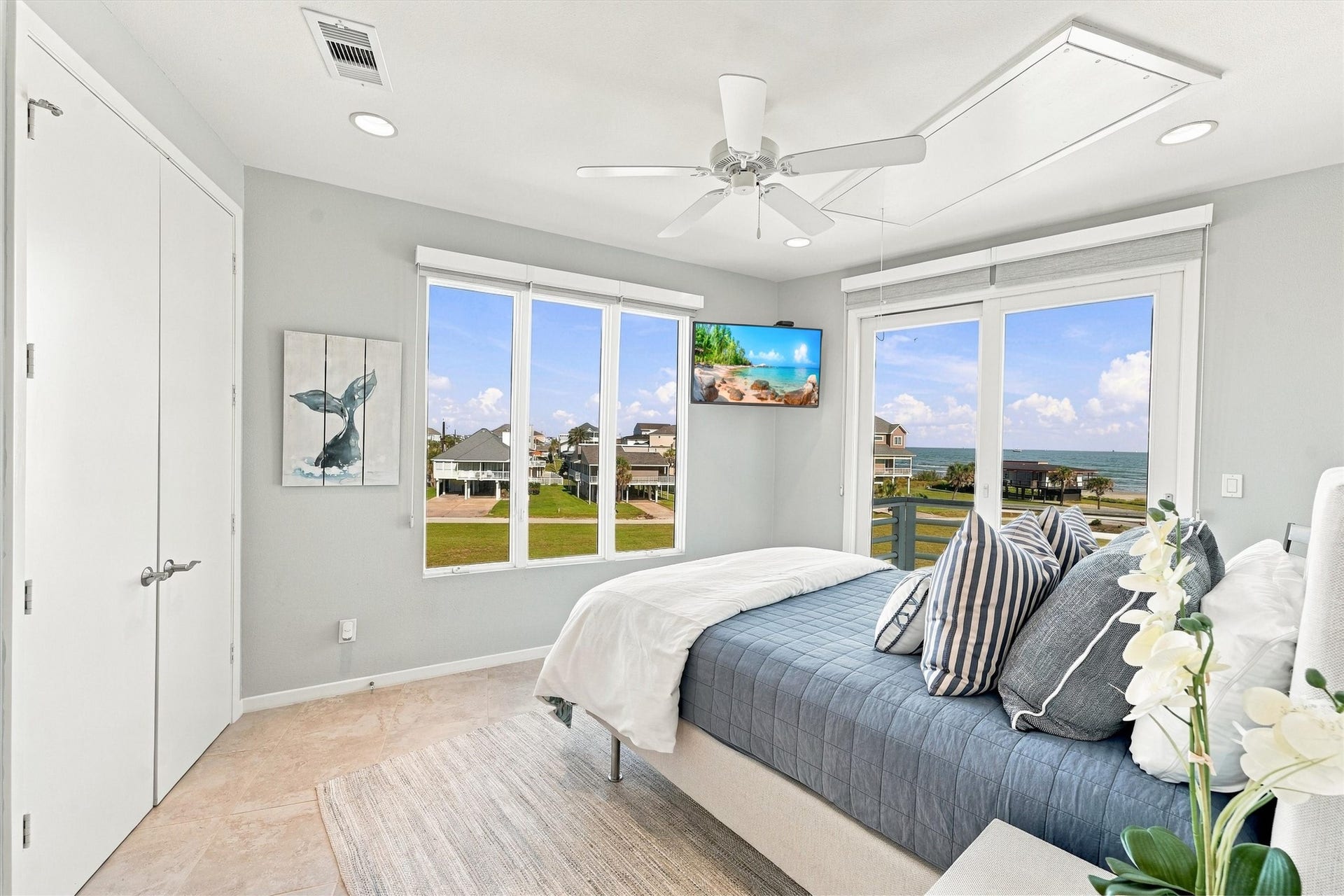 4207 Barataria Court, Galveston, TX 77554 Wake to blue skies and the water stretching toward the horizon. Tall windows and sliding glass doors fill this bedroom with natural light, offering a daily reminder that the beach is only steps away.
