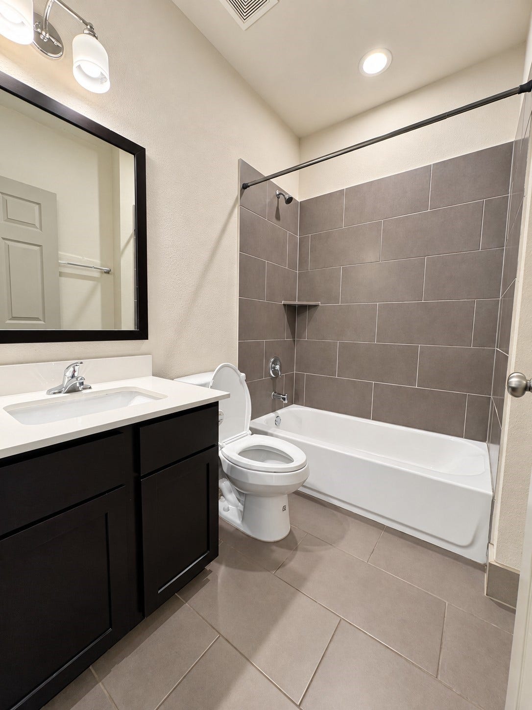 1660 Hawthorne Street, Houston, TX 77006 Representative unit bathroom. Full bathroom within one of the residential units, featuring a tiled tub and shower surround, vanity, dark cabinetry, tiled flooring, and recessed lighting.