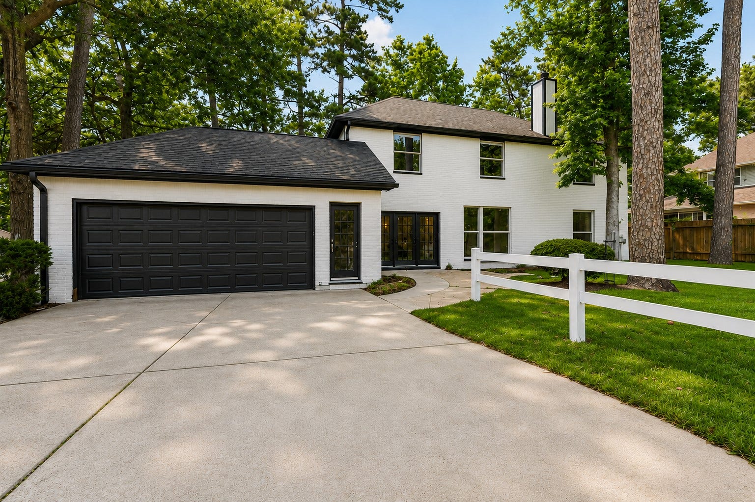 523 Rampart Lane, Conroe, TX 77302 Charming two-story home with a sleek black and white exterior, featuring a spacious driveway leading to a two-car garage, all set amidst a beautifully landscaped, tree-lined yard. Photo digitally enhanced.