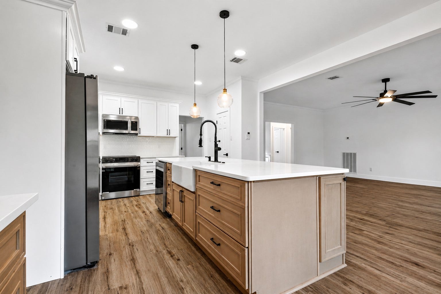 523 Rampart Lane, Conroe, TX 77302 Modern kitchen with a spacious open layout, featuring sleek stainless steel appliances, elegant pendant lighting, and a large island with ample storage and counter space.