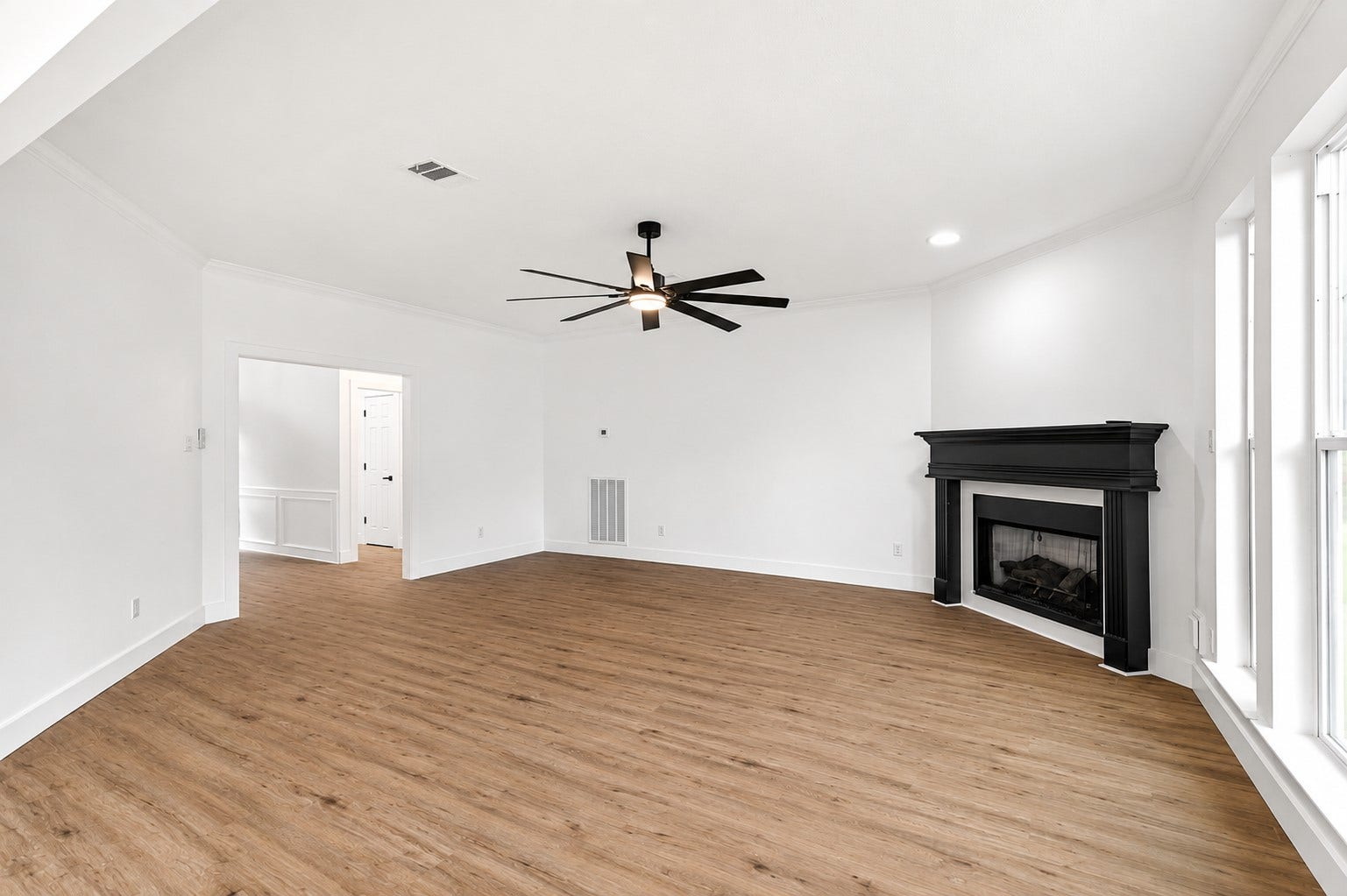 523 Rampart Lane, Conroe, TX 77302 Spacious living room with elegant luxury vinyl flooring, a sleek black fireplace, and abundant natural light streaming through large windows.