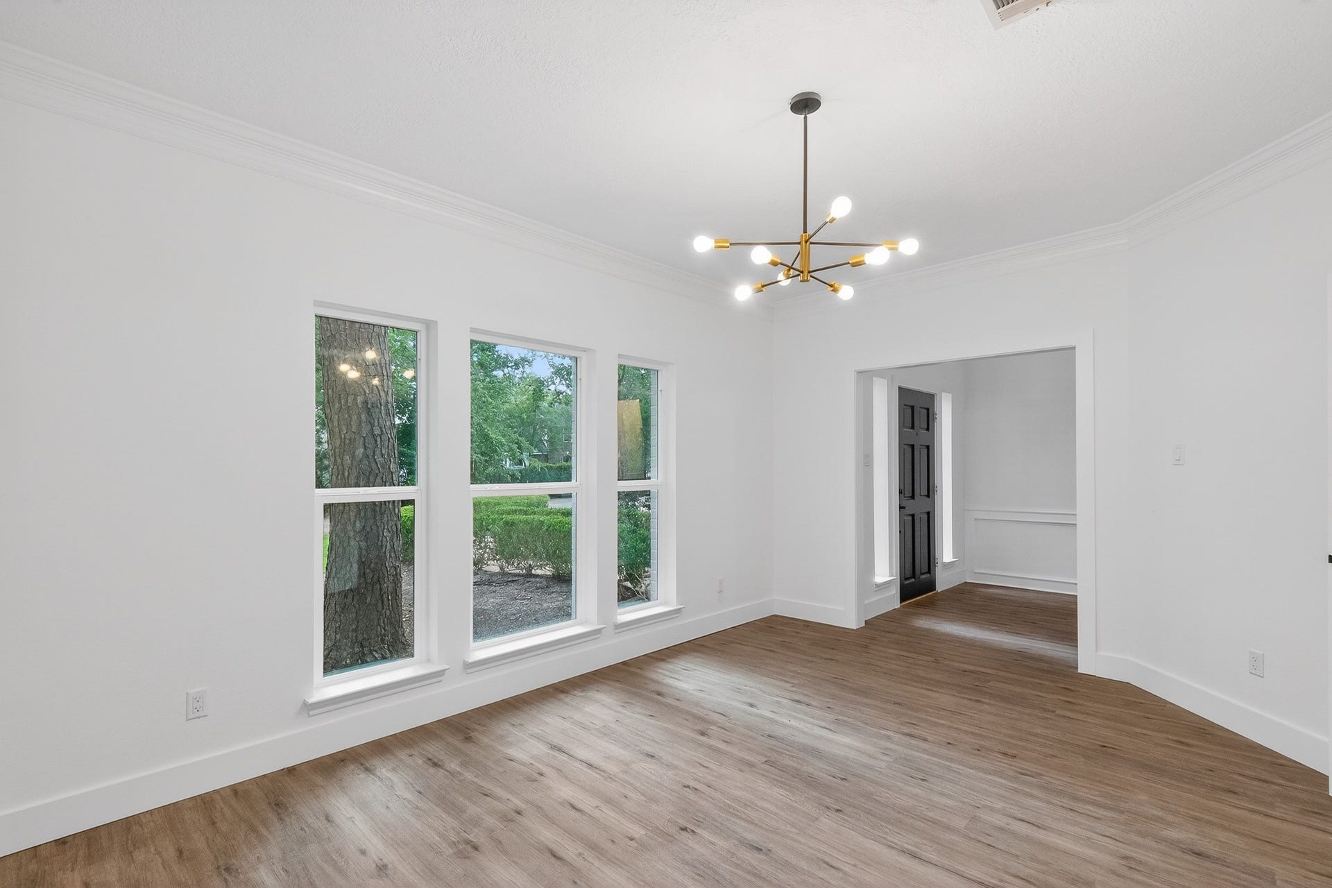 523 Rampart Lane, Conroe, TX 77302 Bright dining area featuring large windows, modern chandelier, and elegant vinyl flooring.