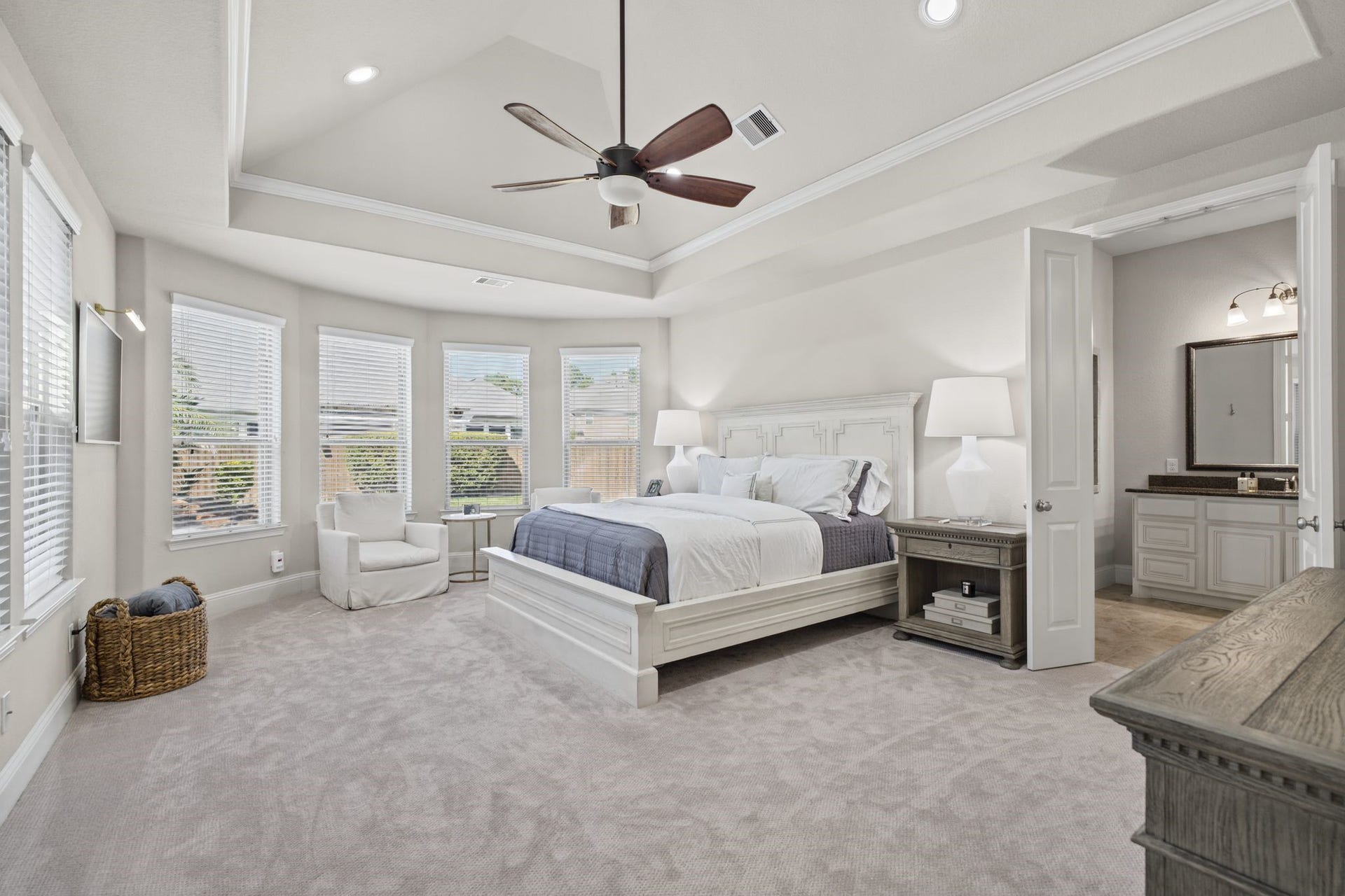 The spacious primary retreat offers an elegant tray ceiling, abundant natural light, and a relaxing sitting area, creating a peaceful and luxurious escape.