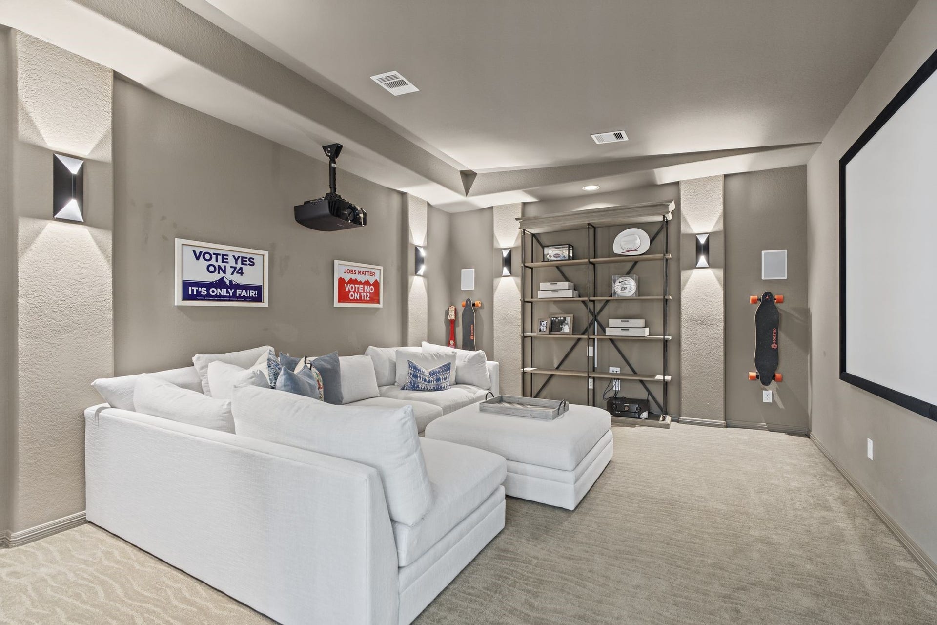 A dedicated media room offers the perfect retreat for movie nights or relaxing in comfort, featuring a large projection screen, elegant wall sconces, designer carpeting, and ample space for oversized seatingcreating a luxurious, theater-inspired experience right at home.