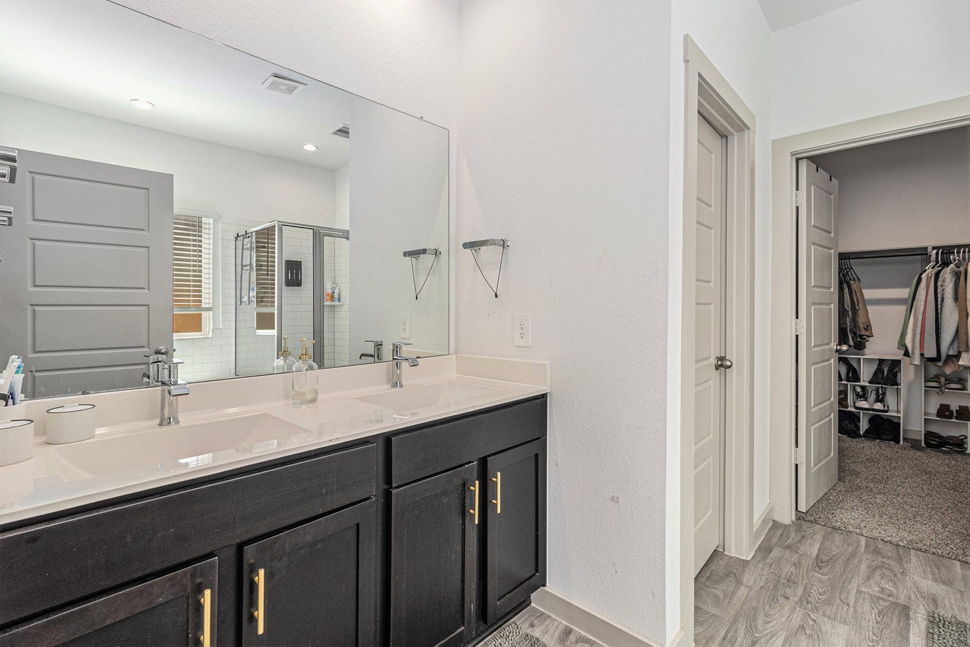 Primary bath features a large vanity with dual sinks and convenient access to the spacious walk-in closet.