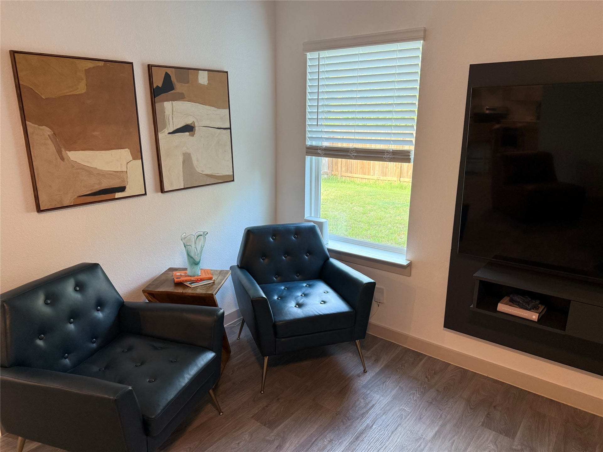 Another view of the inviting living area showcasing abundant natural light, updated neutral paint, luxury vinyl plank flooring, and flexible space for additional seating or a cozy reading area.