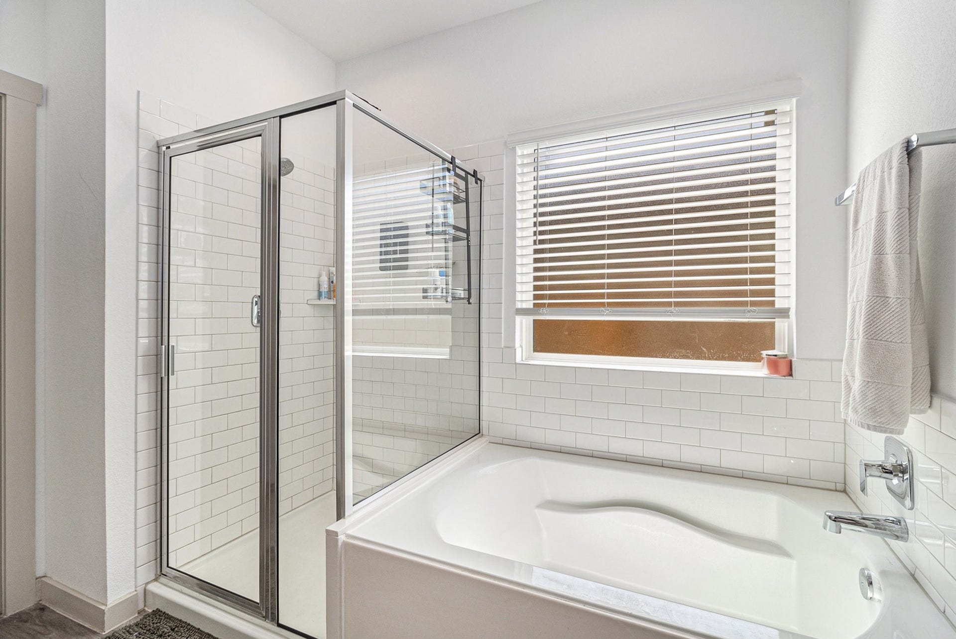 Primary bath includes a separate soaking tub and glass-enclosed shower with classic subway tile surround.