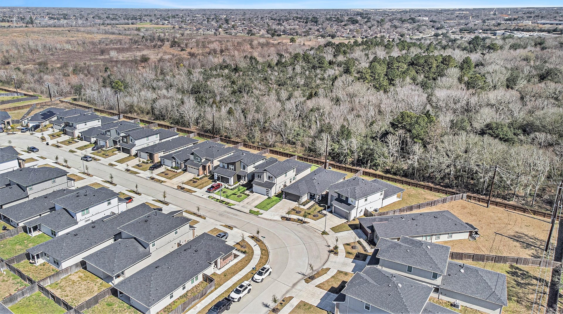 Elevated aerial view showcasing the neighborhood setting and expansive wooded area beyond the community.