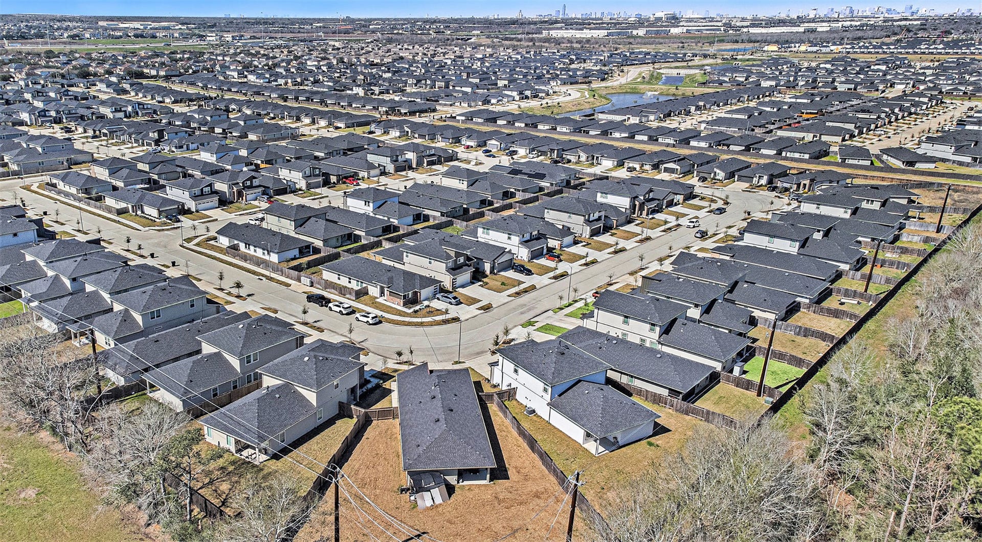 Expansive aerial view showcasing the surrounding community, neighborhood layout, and Houston skyline in the distance. Photo taken prior to the addition of the deck and pergola.