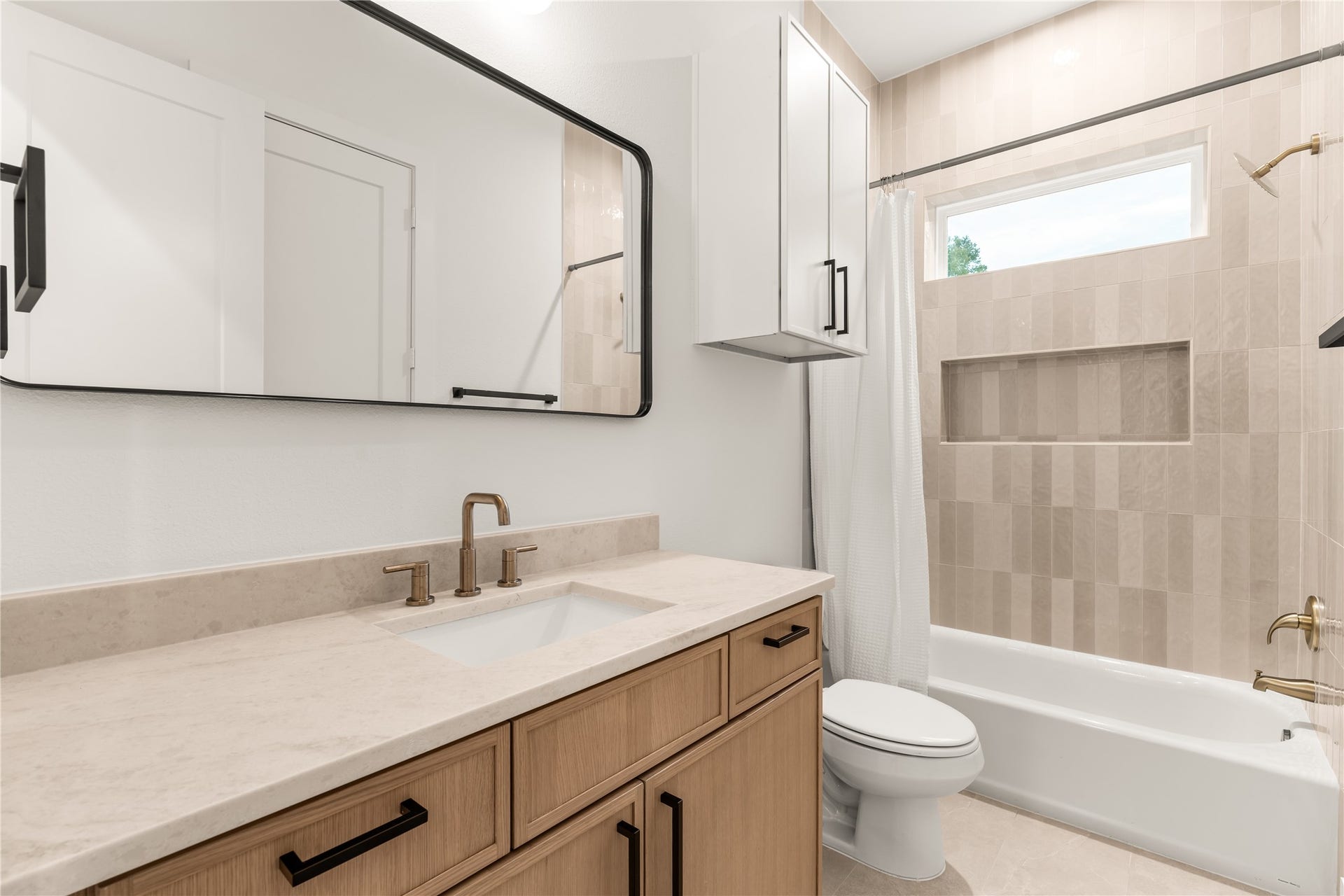 6619 Avenue Q, #B, Houston, TX 77011 Stylish full secondary bathroom featuring warm wood cabinetry, quartz countertops, matte black hardware, and custom tilework.