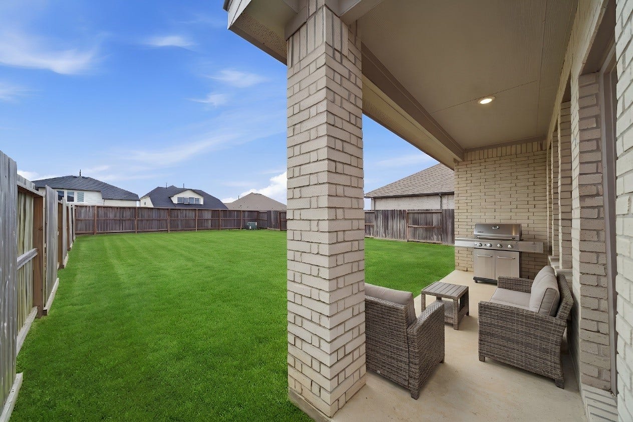 2446 Rosemary Sage Drive, Brookshire, TX 77423 Spacious backyard featuring a well-maintained lawn and covered patio area, offering a comfortable outdoor space for relaxing, dining, and entertaining. Enjoy your morning coffee.