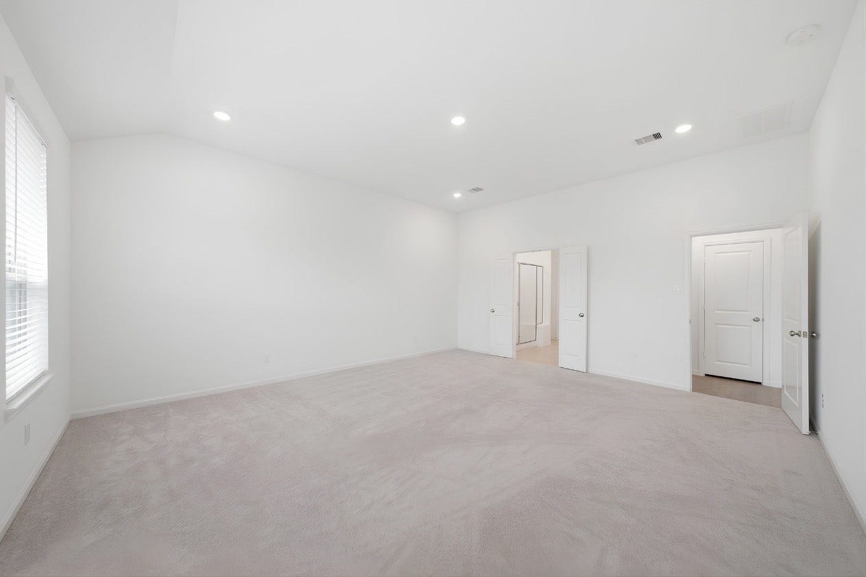 2446 Rosemary Sage Drive, Brookshire, TX 77423 Another view of the spacious first-floor primary suite, highlighting the abundance of windows that fill the room with warm natural light and create a bright, inviting retreat.