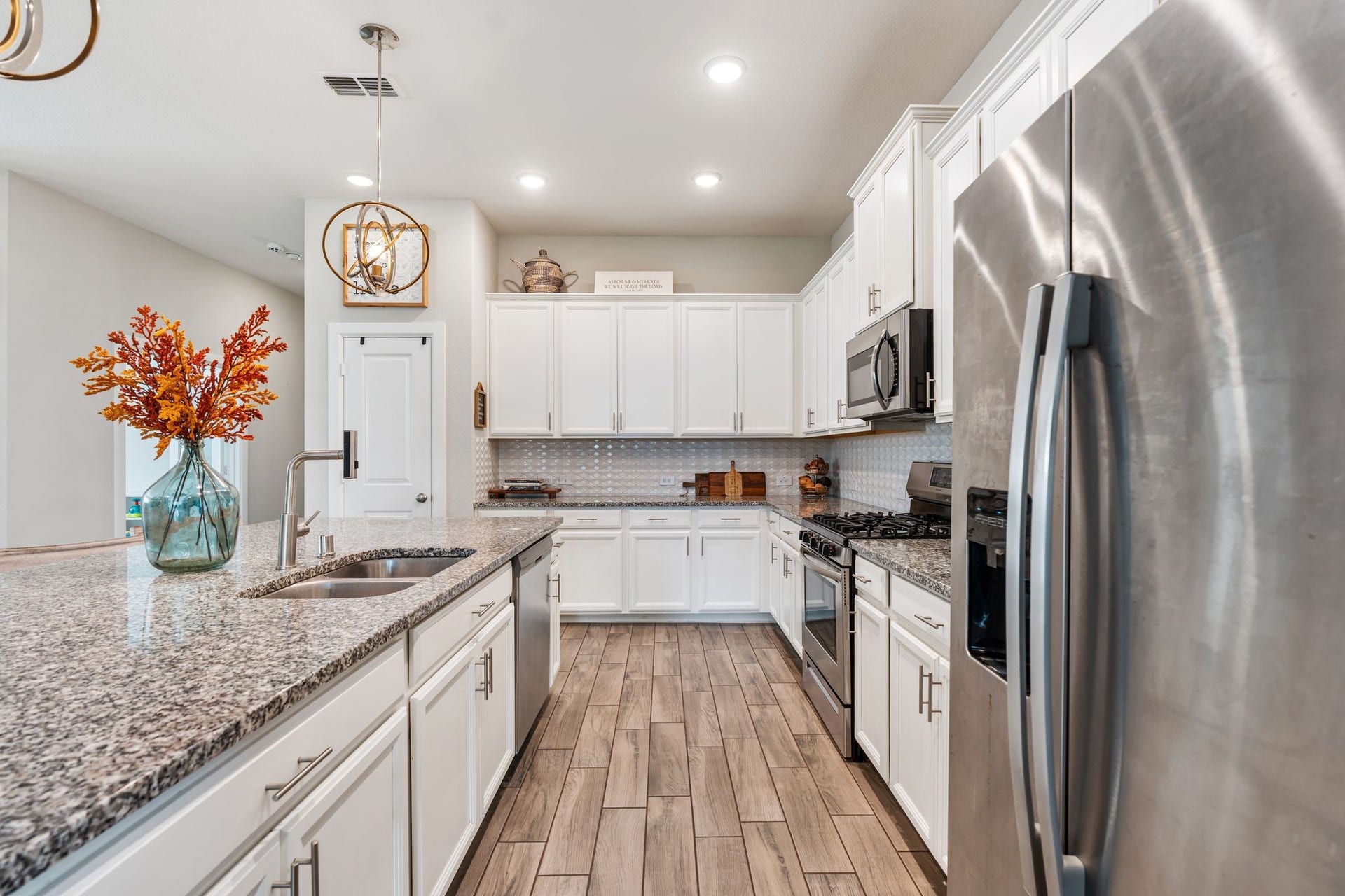 Beautiful pendant lighting, gas stove and stainless steel appliances.