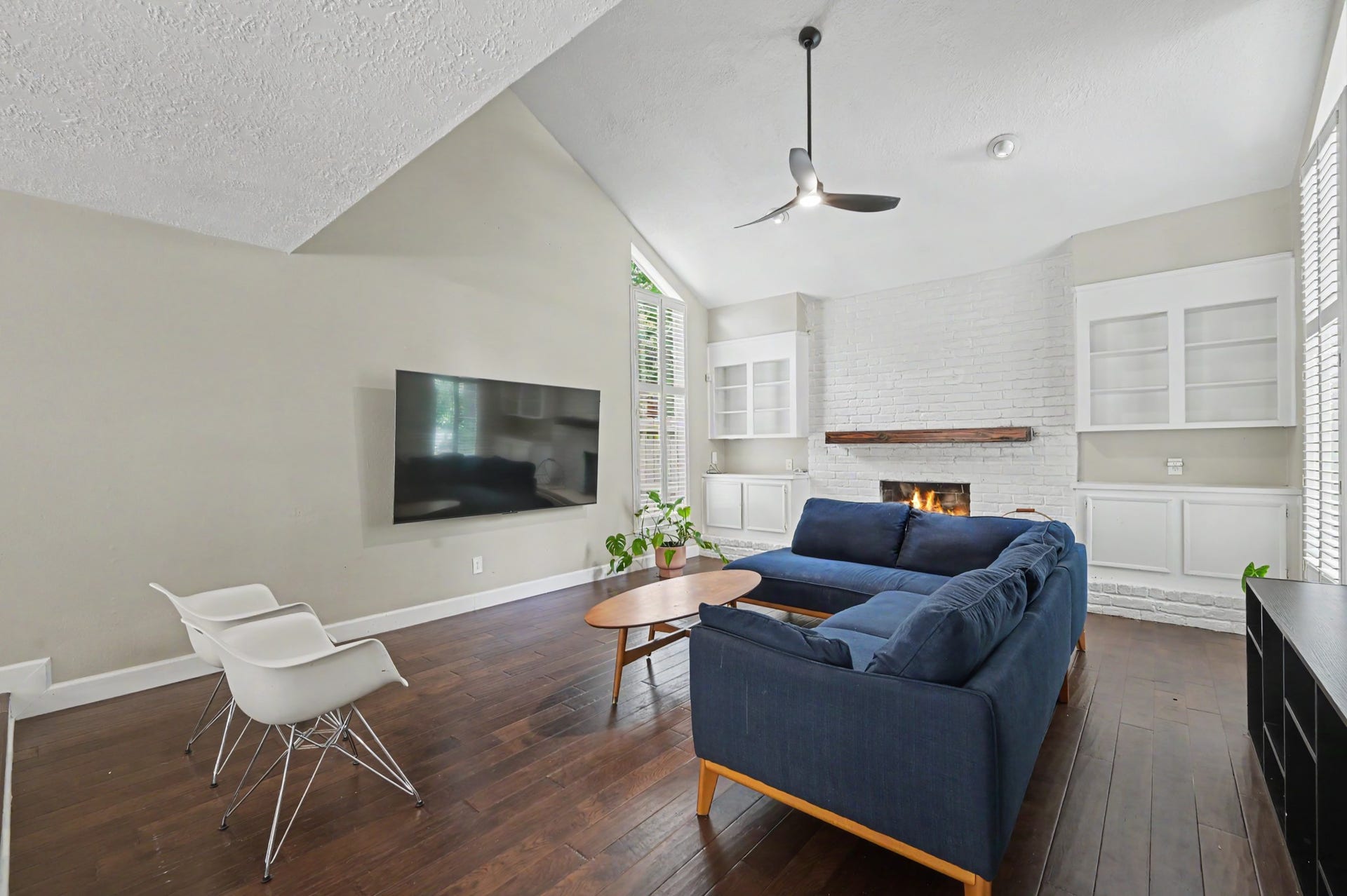 2314 Chestnut Oak Place, The Woodlands, TX 77380 Spacious living room with a vaulted ceiling, engineered wood flooring and a white painted brick fireplace surrounded by built-in cabinetry.