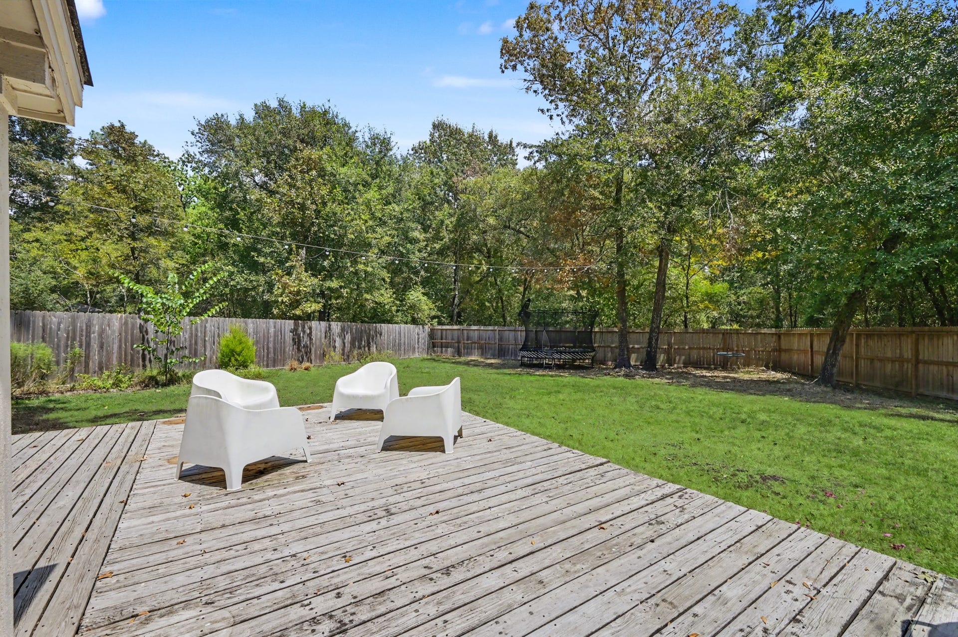 2314 Chestnut Oak Place, The Woodlands, TX 77380 Mature trees and a wooded backdrop surround the large deck and backyard, offering a relaxing outdoor setting