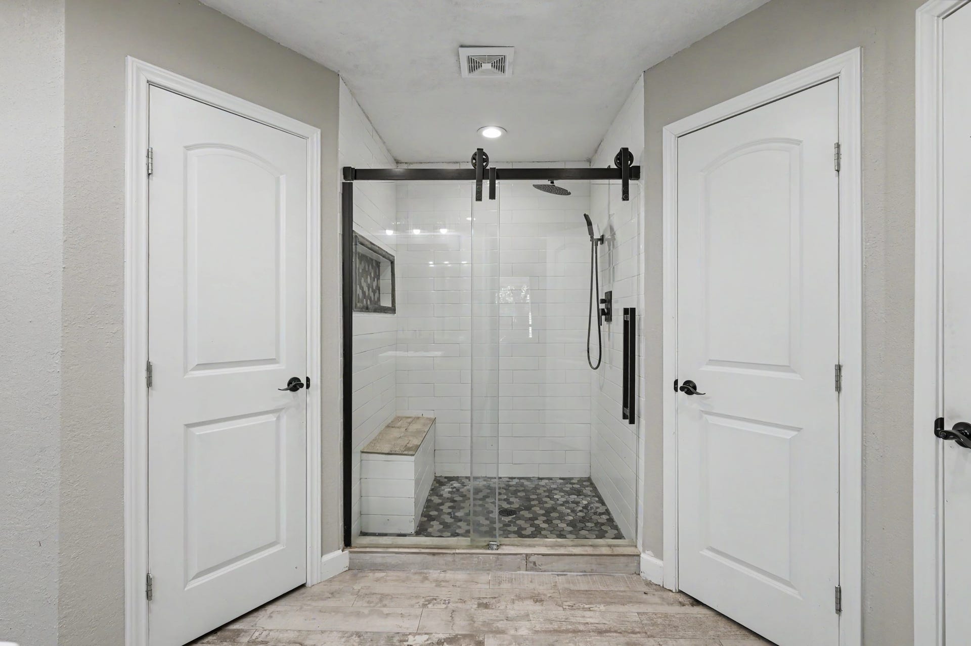 2314 Chestnut Oak Place, The Woodlands, TX 77380 The updated primary bath features a large walk-in shower with bench seating, a built-in niche, rainfall and handheld showerheads, and sliding glass doors.