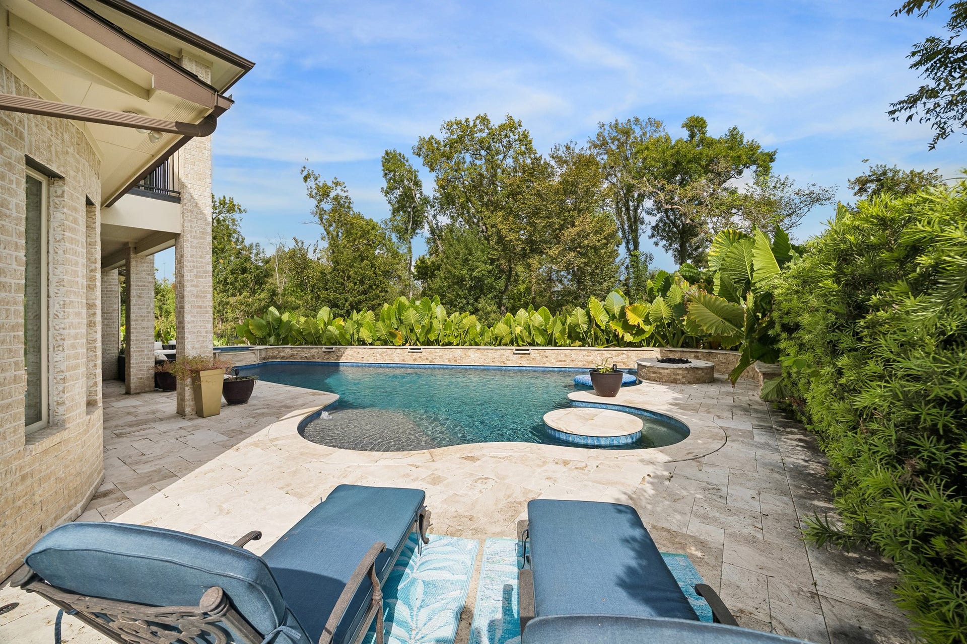 5018 Southampton Road, Missouri City, TX 77459 Luxurious outdoor oasis featuring a sparkling pool with integrated spa, surrounded by lush greenery and elegant stone patio, perfect for relaxation and entertaining.