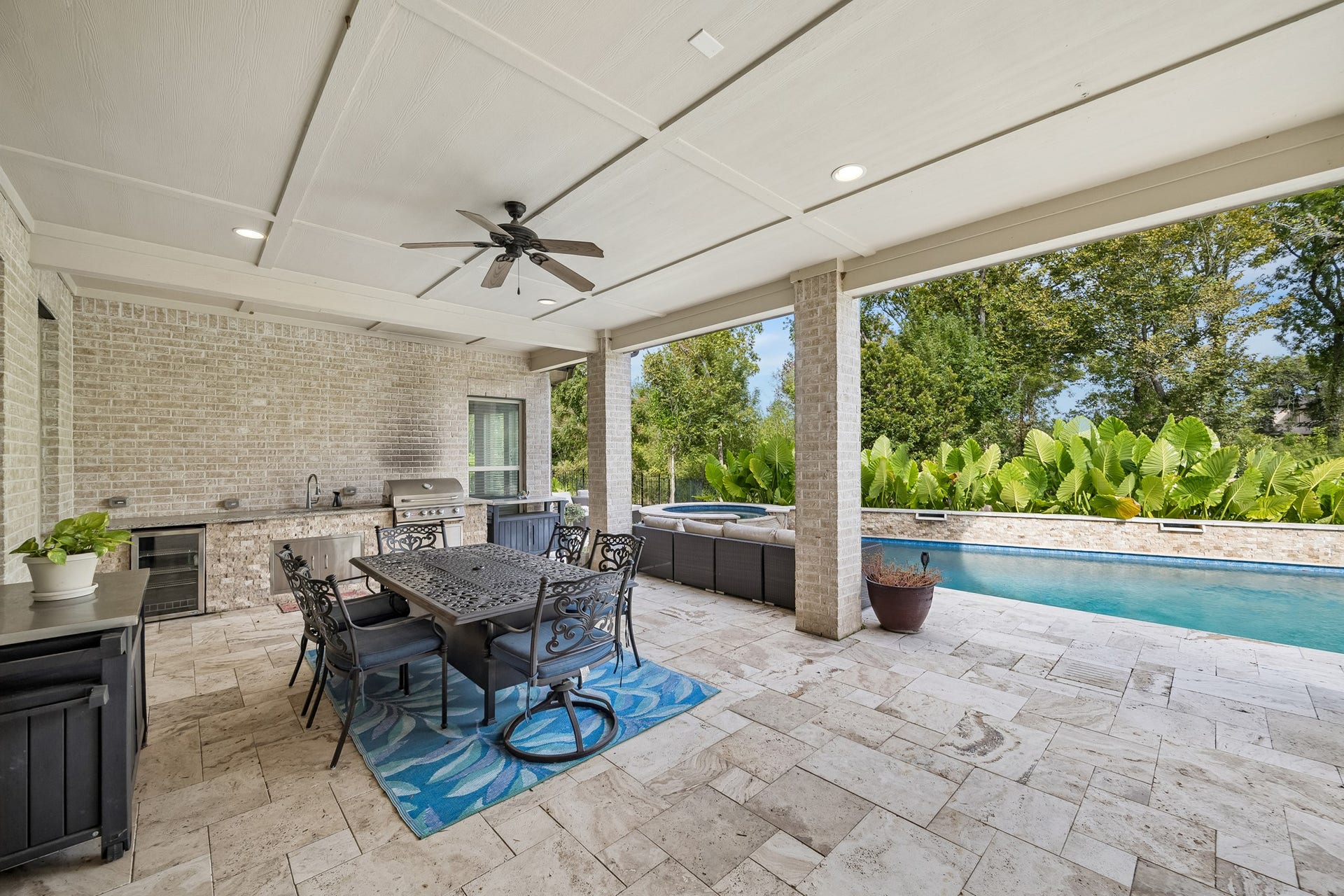 5018 Southampton Road, Missouri City, TX 77459 Experience outdoor luxury with this spacious covered patio, featuring a modern outdoor kitchen and a refreshing pool surrounded by lush greenery.