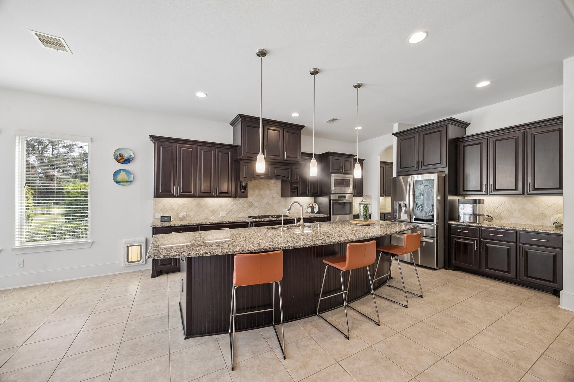 5018 Southampton Road, Missouri City, TX 77459 Spacious kitchen with elegant dark wood cabinetry, granite countertops, and a large island with modern pendant lighting, perfect for entertaining.