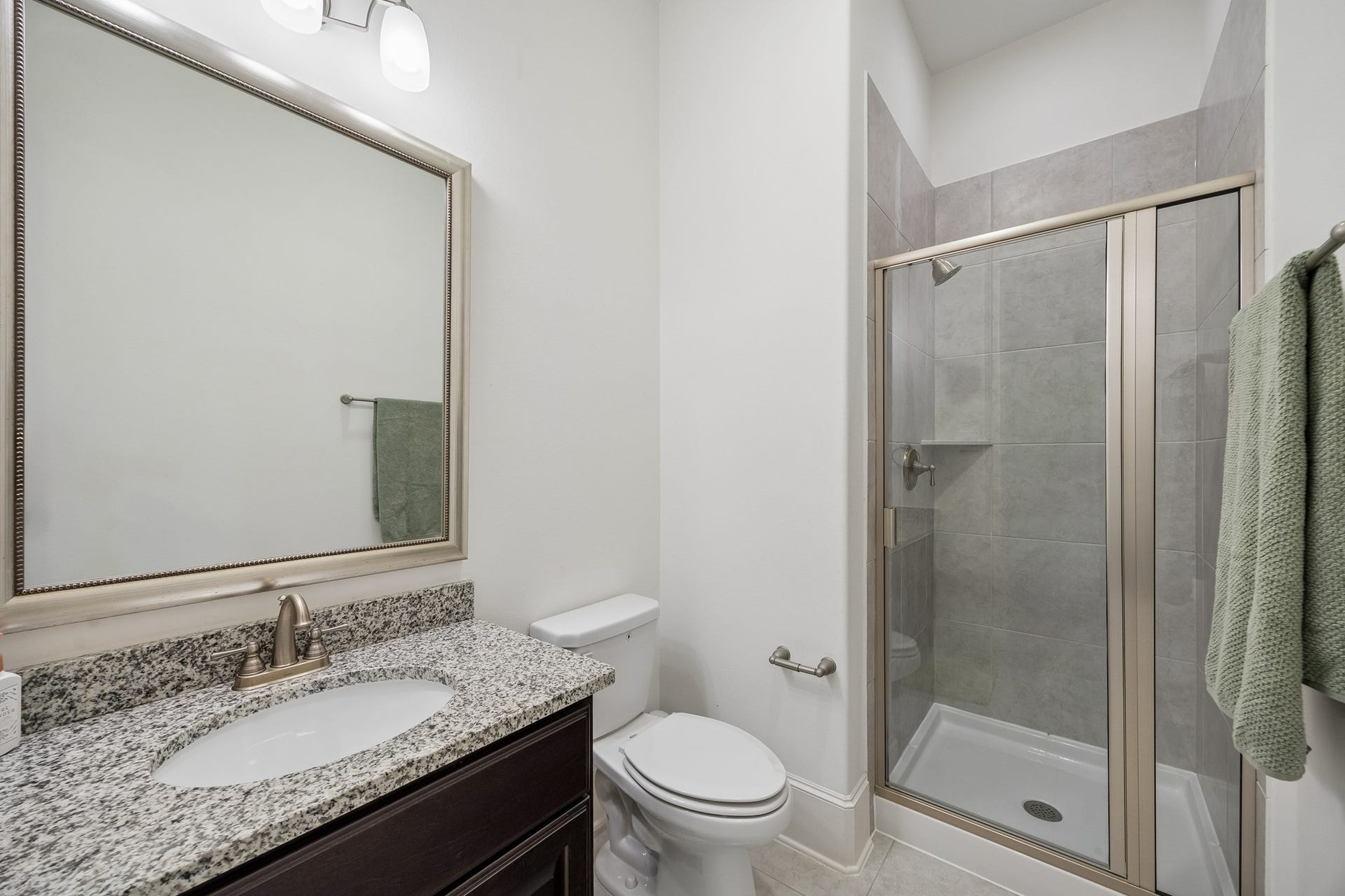 5018 Southampton Road, Missouri City, TX 77459 This elegant bathroom featuring a spacious glass-enclosed shower, sleek granite countertop, and modern fixtures for a refined touch is located in the 1st floor secondary bedroom.