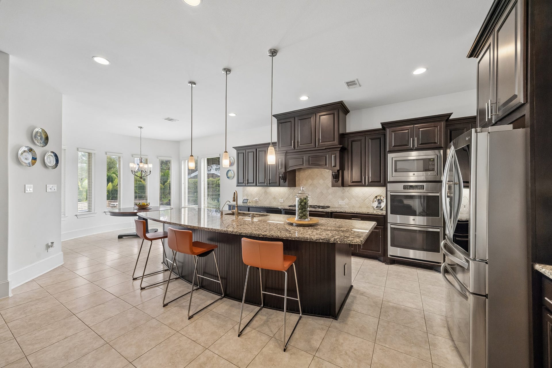 5018 Southampton Road, Missouri City, TX 77459 Spacious kitchen with abundant dark wood cabinetry, a large granite island, stainless steel appliances, and natural light from surrounding windows.