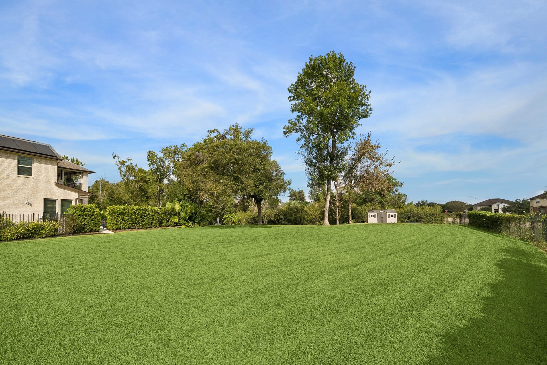 5018 Southampton Road, Missouri City, TX 77459 Expansive backyard with lush green lawn, mature trees, and ample space for outdoor activities, adjacent to a charming two-story home.