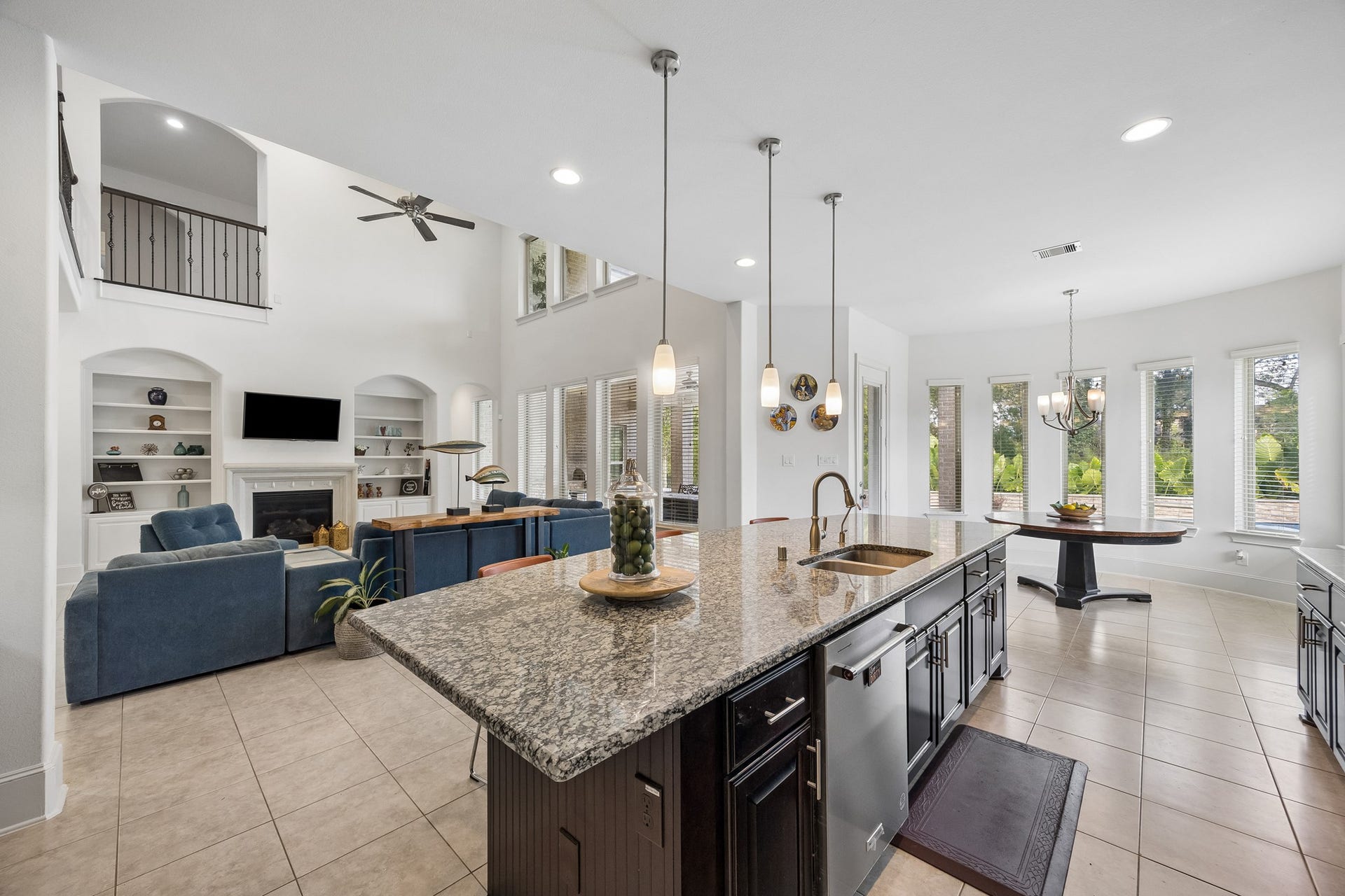 5018 Southampton Road, Missouri City, TX 77459 Spacious open-concept living area with high ceilings, featuring a modern kitchen with granite countertops, cozy living room with a fireplace, and ample natural light from large windows.