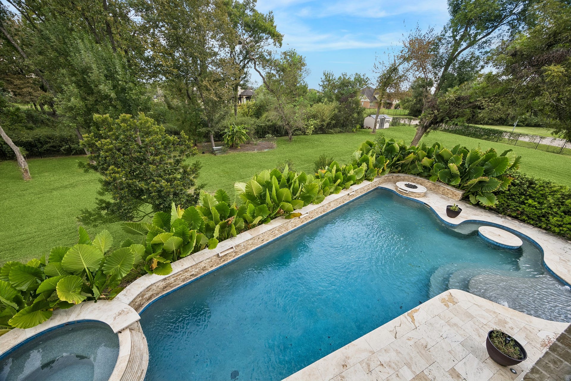 5018 Southampton Road, Missouri City, TX 77459 Enjoy serene views from a luxurious backyard featuring a sparkling pool and lush greenery, perfect for relaxation and entertaining.