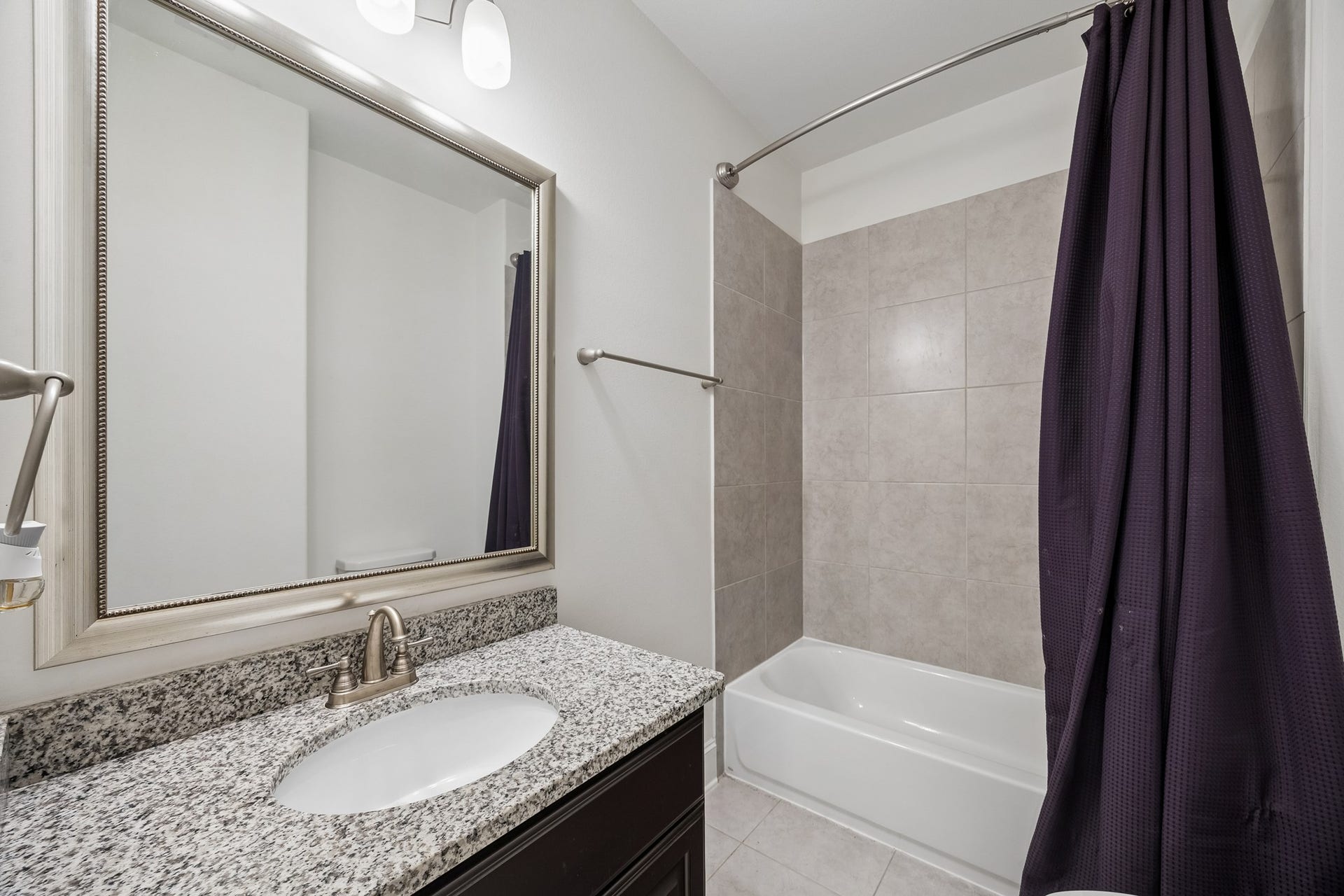 5018 Southampton Road, Missouri City, TX 77459 Chic bathroom located in one of the 2nd floor secondary bedrooms features a granite countertop with an undermount sink, elegant framed mirror, and a modern tub.