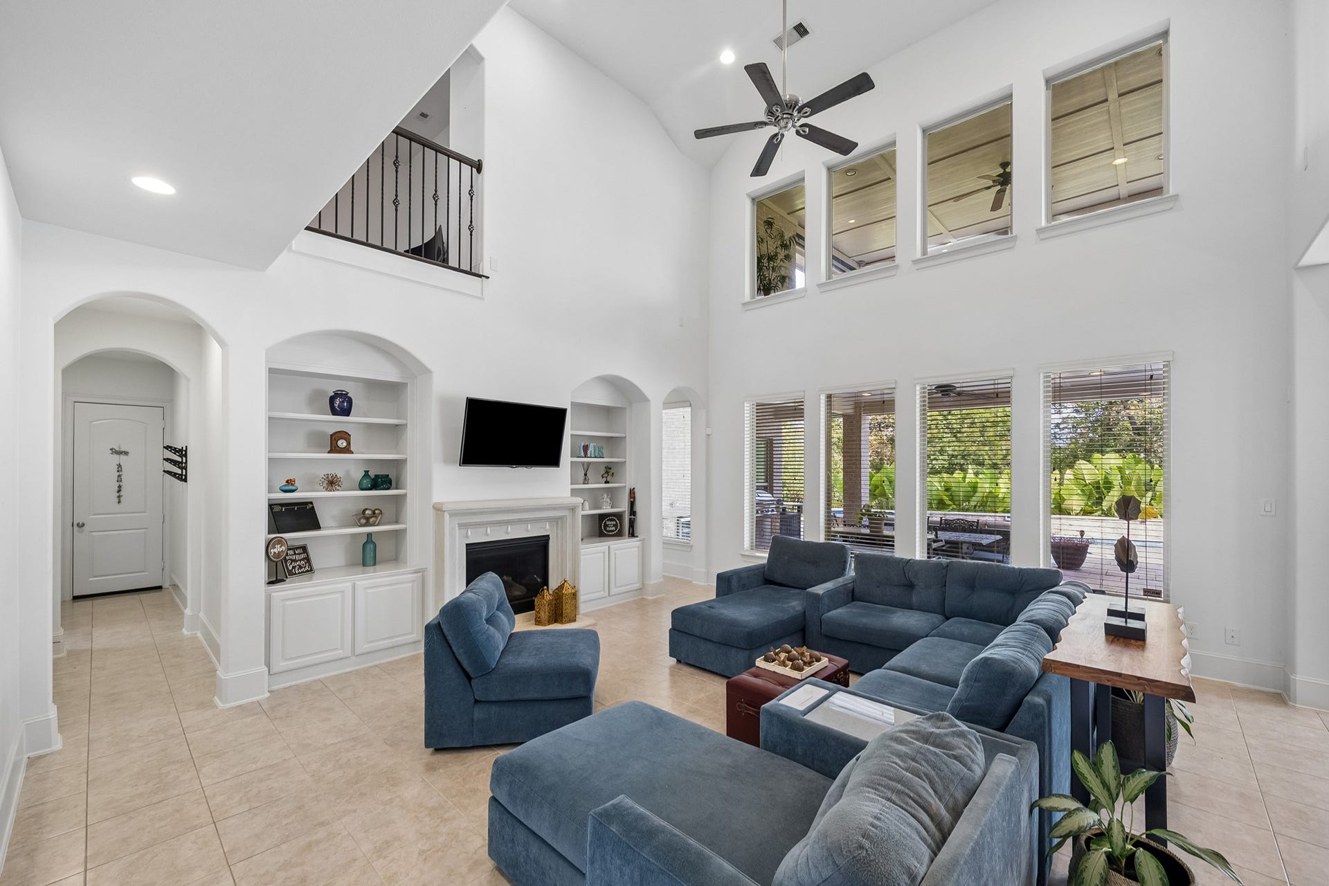 5018 Southampton Road, Missouri City, TX 77459 Spacious living room with high ceilings, abundant natural light, and elegant built-in shelving surrounding a cozy fireplace, offering a perfect blend of style and comfort.