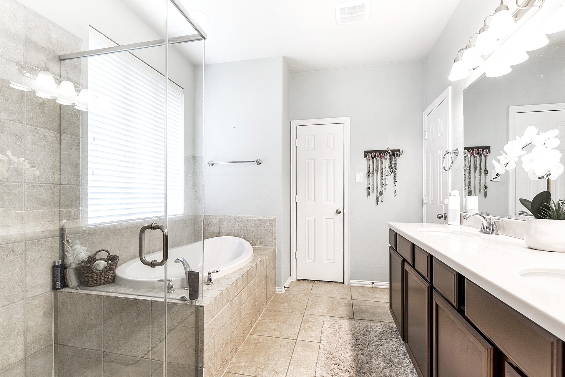 The ensuite bathroom boasts double sinks, a seamless glass shower, and soaking tubs, providing both functionality and luxury for your daily routines and relaxation.