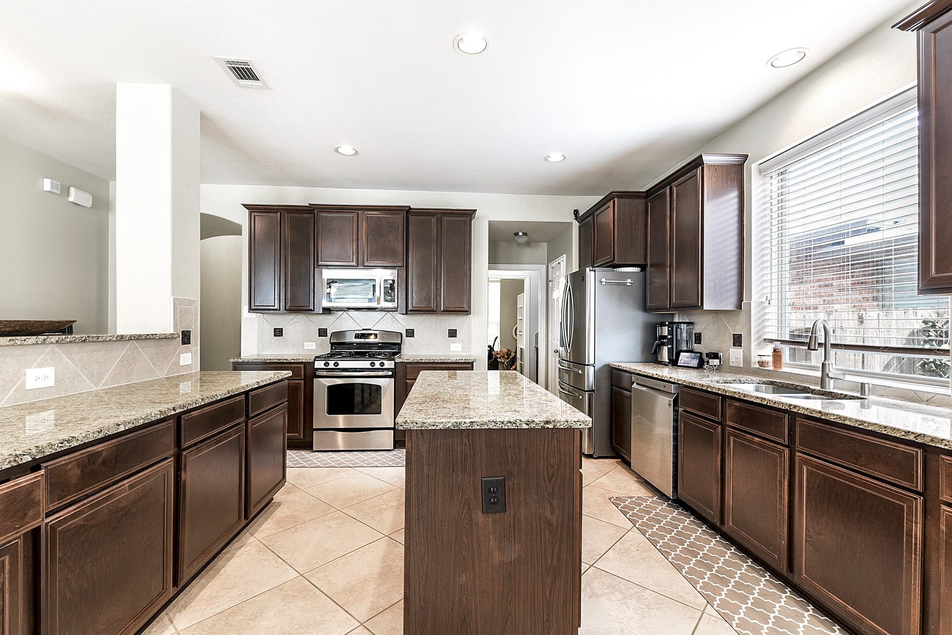 Another view of the kitchen highlights the spacious layout and abundant storage options. Electrical outlets are conveniently located on the breakfast bars, allowing for easy use of small appliances. The gas stove and stainless steel appliances add both style and functionality to the space. Additionally, the refrigerator comes included with the home, making it move-in ready for your convenience.