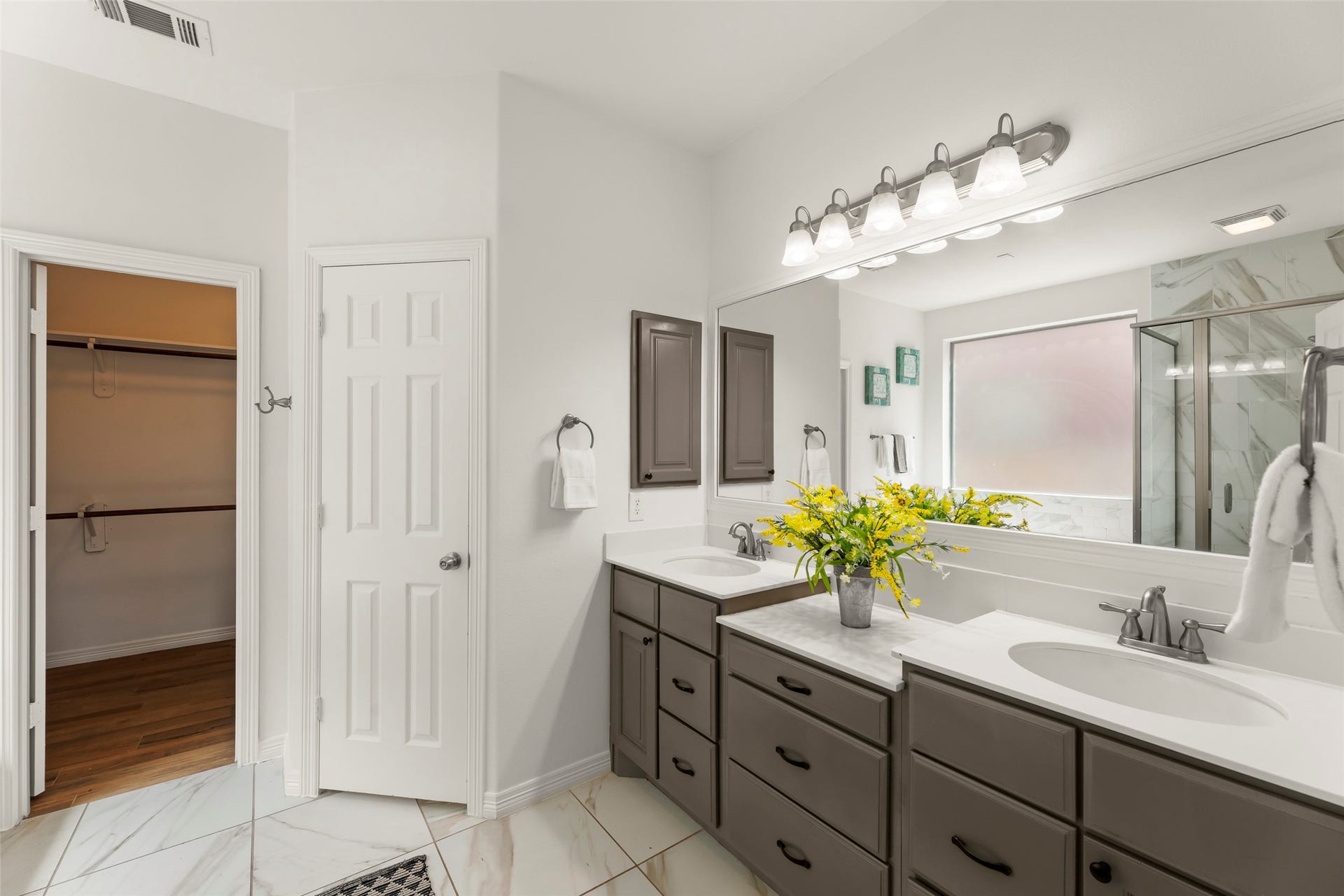 4534 Montcliff Bend Lane, Sugar Land, TX 77479 Dual-sink vanity with sleek cabinetry, a spacious walk-in closet, and a large window providing natural light.