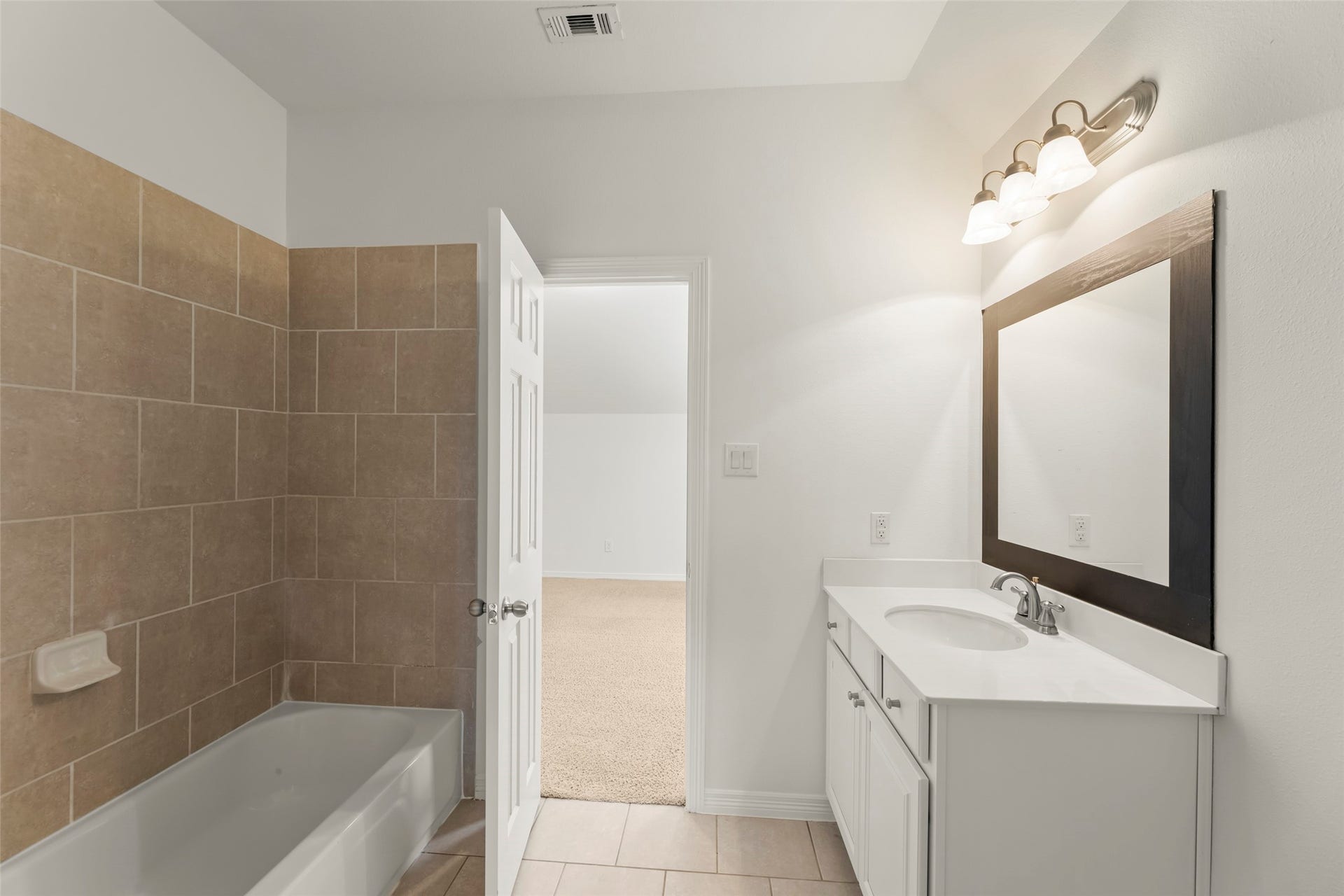 4534 Montcliff Bend Lane, Sugar Land, TX 77479 Stylish bathroom featuring a tiled bathtub, modern vanity with ample storage, and a sleek framed mirror.