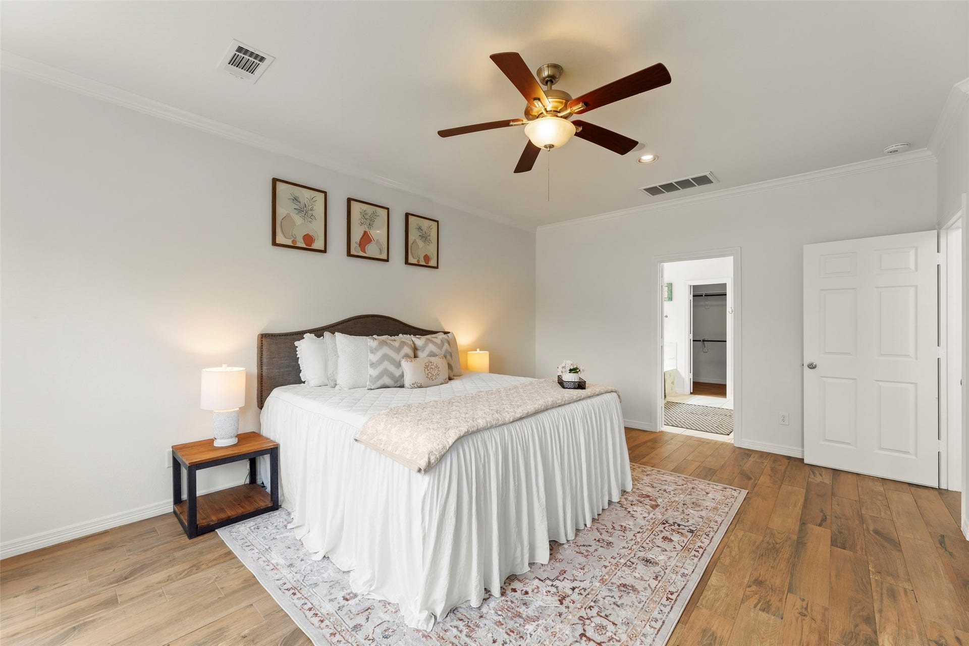 4534 Montcliff Bend Lane, Sugar Land, TX 77479 Primary bedroom with elegant wood-like floors, a cozy bed, and soft lighting. Decorated with tasteful artwork, it offers a serene retreat with an attached bathroom.