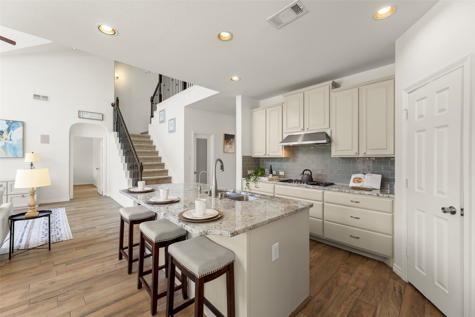 4534 Montcliff Bend Lane, Sugar Land, TX 77479 Open-concept kitchen with granite countertops, stylish bar seating, and modern cabinetry, seamlessly connected to a bright family room area with a grand staircase.