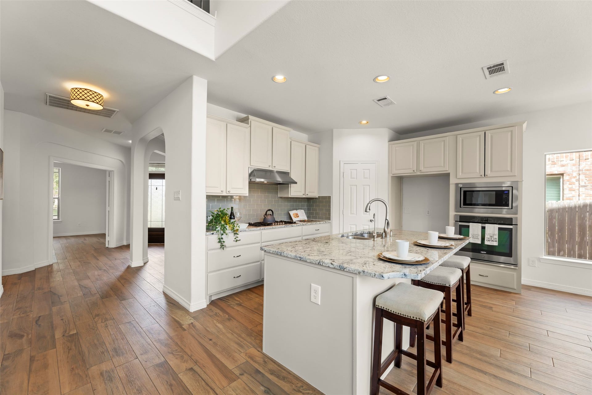 4534 Montcliff Bend Lane, Sugar Land, TX 77479 Vibrant inviting kitchen with modern appliances, an elegant granite island with seating, and warm wood flooring extending into the spacious adjacent areas.