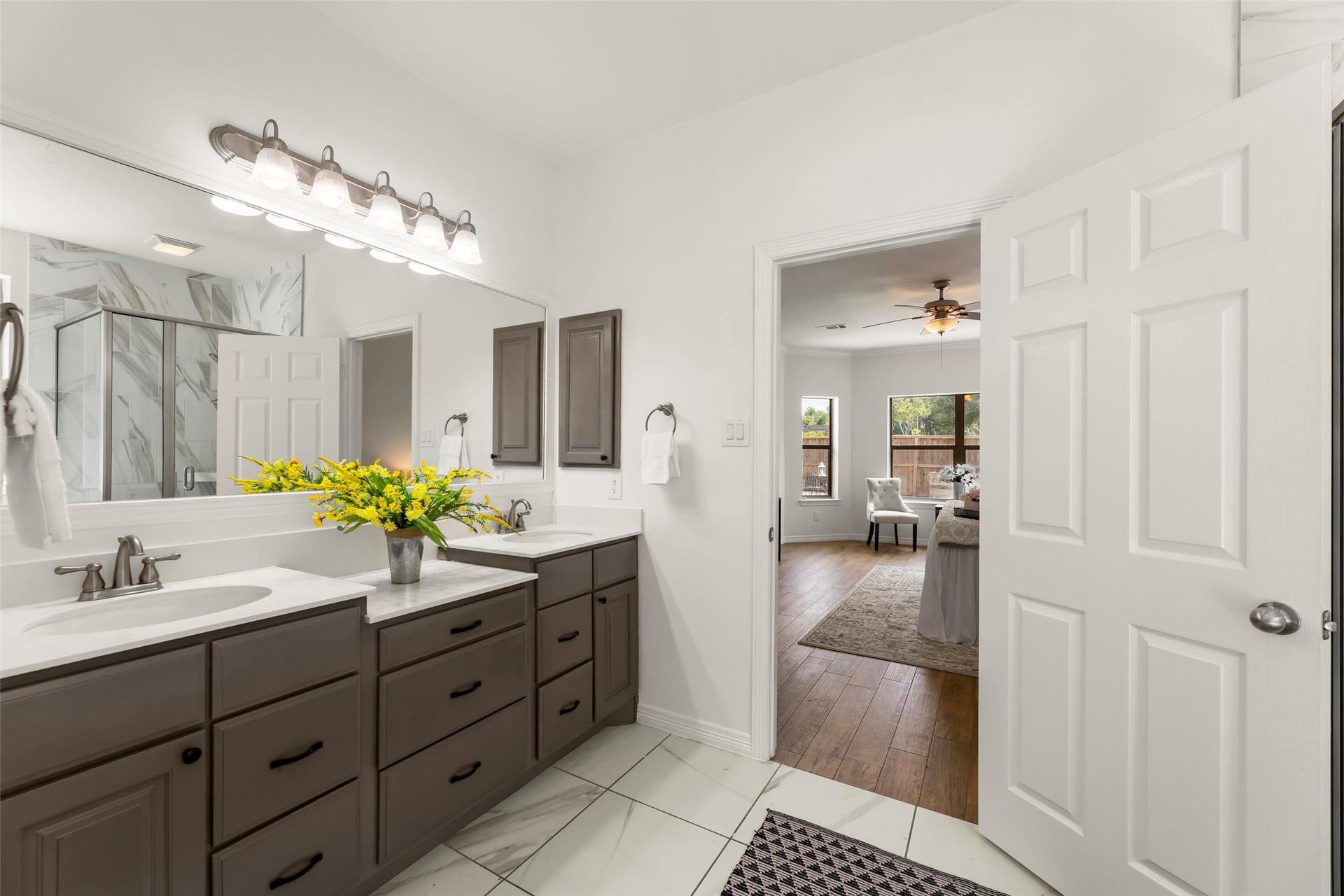 4534 Montcliff Bend Lane, Sugar Land, TX 77479 Primary bathroom with dual sinks, elegant cabinetry, and a walk-in shower, leading to a cozy bedroom with hardwood floors and large windows.