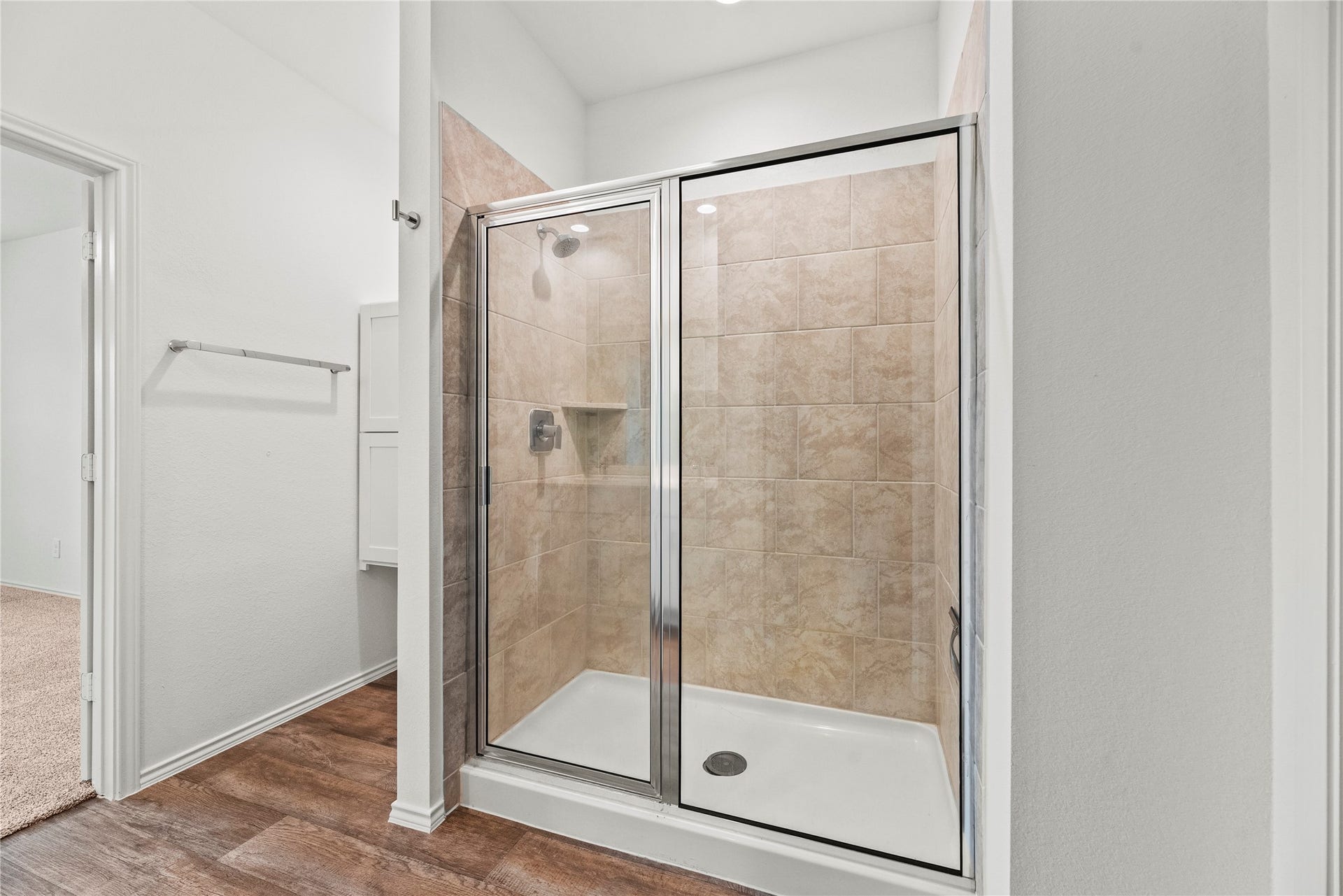 The private bathroom features a spacious walk-in shower with designer tile surrounds and a sleek glass enclosure.