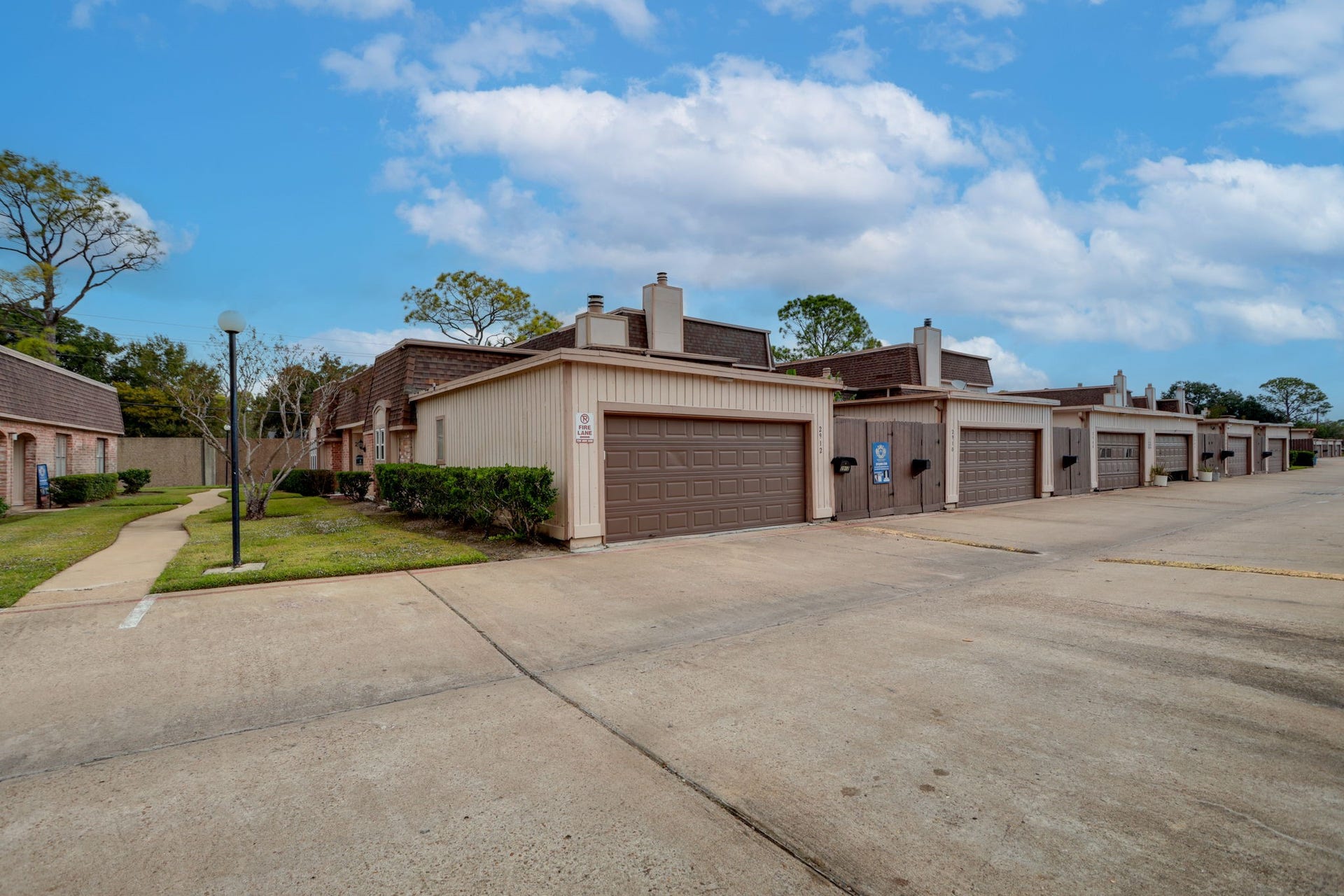 2912 Camelot Lane, Missouri City, TX 77459 The attached two-car garage adds useful parking and storage space to this single-story Quail Valley townhome. Laundry connections are located inside the garage, and an adjacent gate provides access to the fenced patio. This rear perspective shows the convenient relationship between vehicle access, the garage, and the outdoor space.