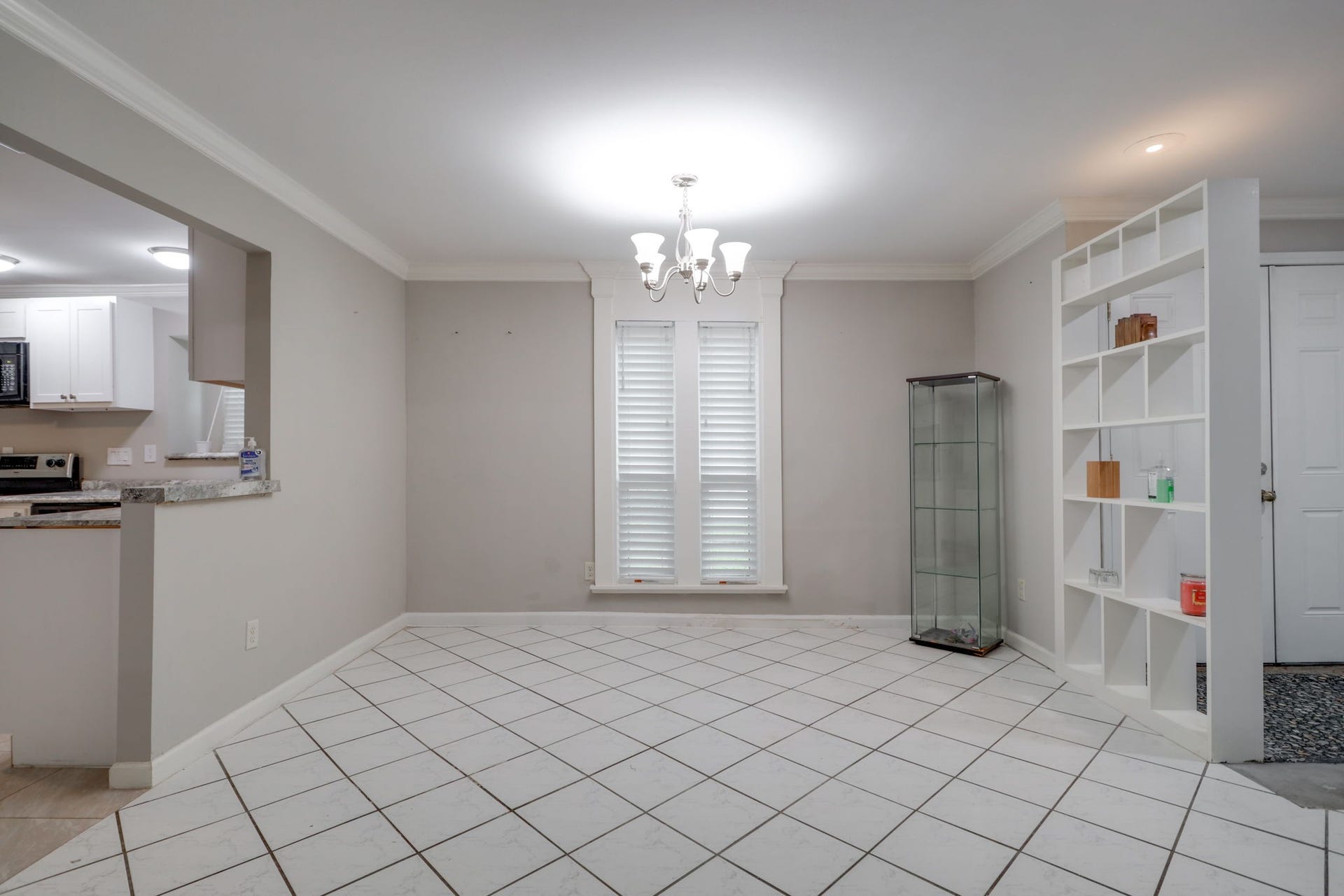 2912 Camelot Lane, Missouri City, TX 77459 Tall windows with blinds bring natural light into the dining room, creating a welcoming setting for meals and conversation. A wide opening connects directly to the kitchen, making serving convenient while maintaining a distinct dining space. Crown molding, neutral walls, and tile flooring carry a consistent look through the adjoining areas.