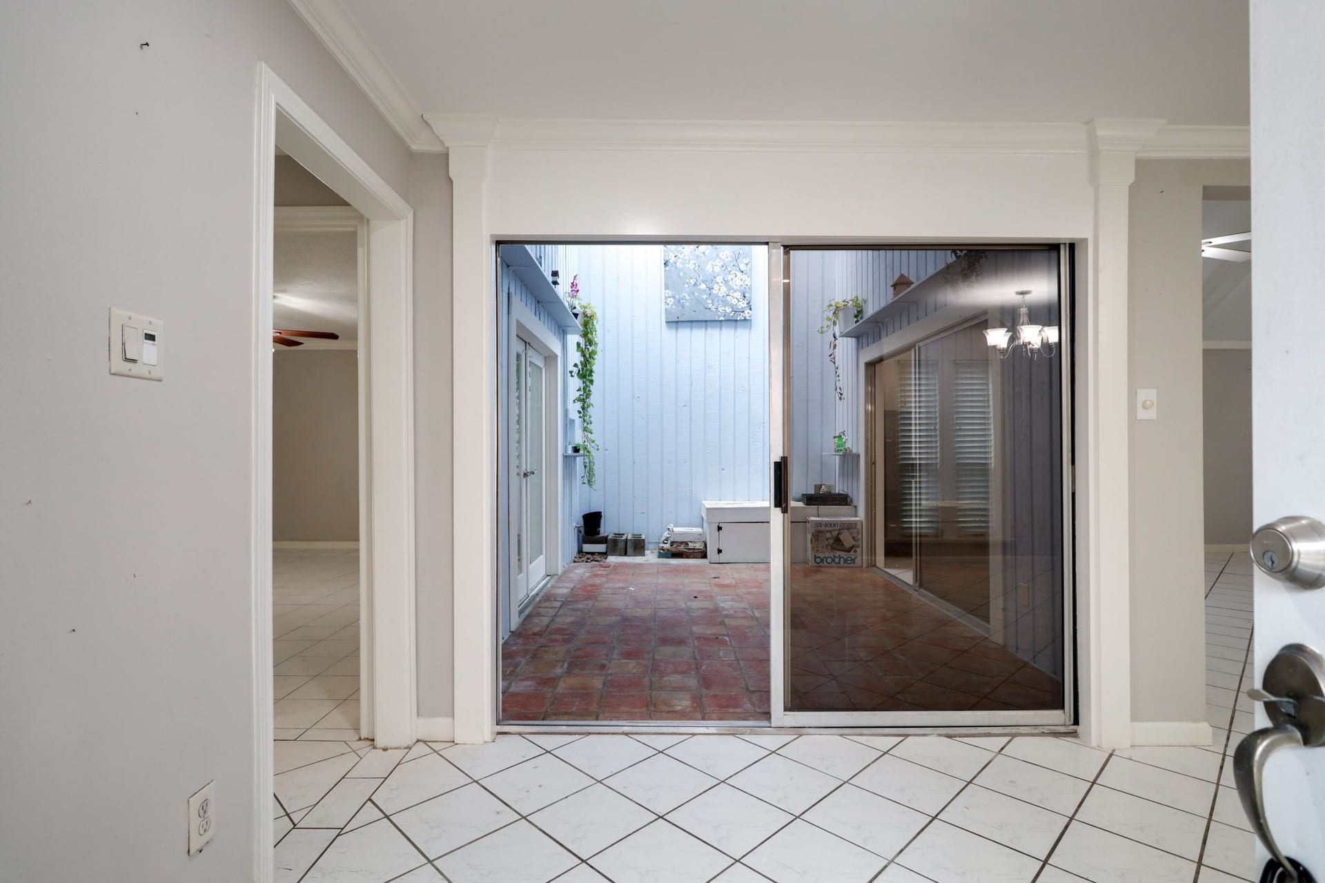 2912 Camelot Lane, Missouri City, TX 77459 The entry introduces one of this Missouri City townhomes most distinctive features: a central atrium visible through sliding glass doors. Tile flooring and wide openings connect the surrounding rooms, while the atrium adds natural light and an appealing interior view. It is a memorable introduction to a floor plan with personality.
