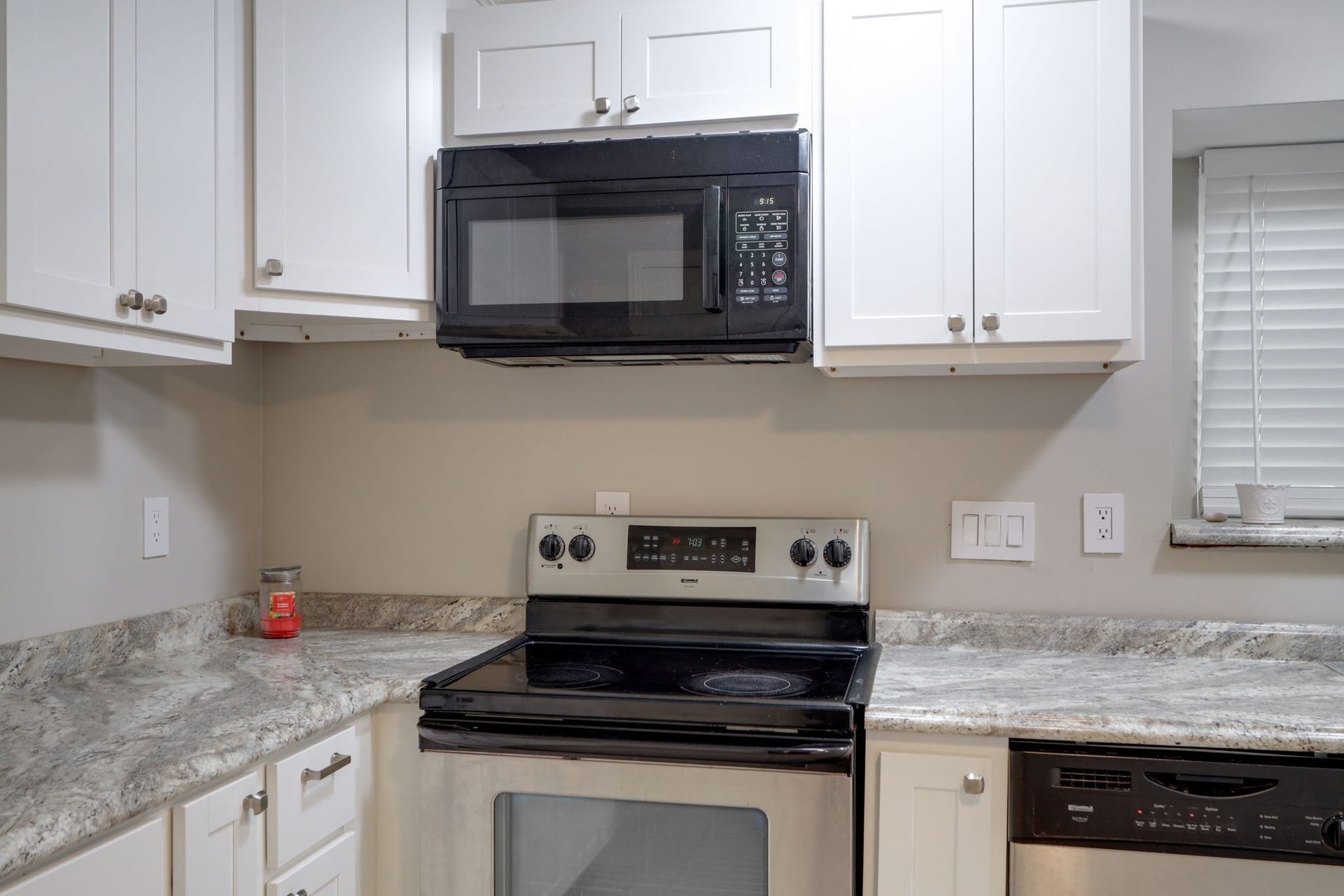 2912 Camelot Lane, Missouri City, TX 77459 A stainless steel electric range and coordinating overhead microwave anchor the kitchens cooking area. Countertop space on both sides provides room for preparation and serving, while white upper and lower cabinets keep cookware and ingredients nearby. The contrasting appliance finishes and cabinetry give this practical workspace a crisp, coordinated appearance.