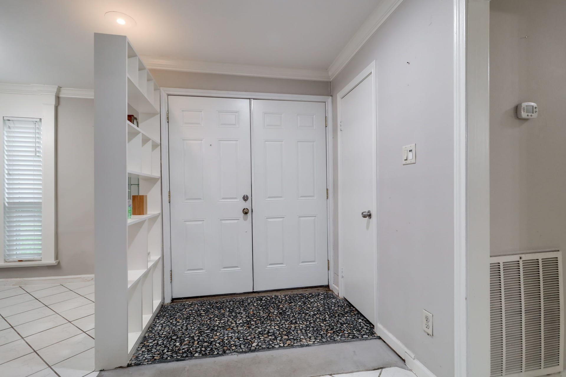2912 Camelot Lane, Missouri City, TX 77459 Double front doors open into a defined foyer with a nearby coat closet for everyday storage. Open display shelving separates the entrance from the dining room without enclosing the space. Neutral finishes and decorative trim create a welcoming transition into this Quail Valley townhomes main living areas.