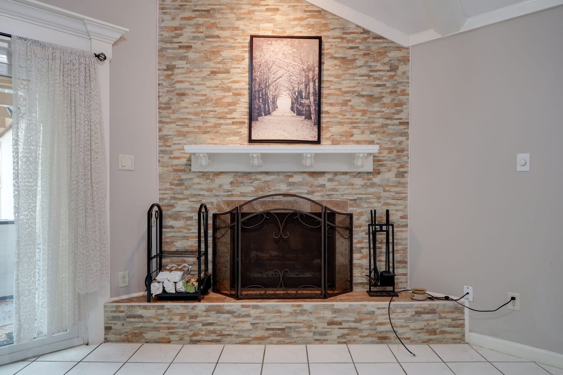 2912 Camelot Lane, Missouri City, TX 77459 A floor-to-ceiling stone fireplace surround brings warmth, texture, and architectural interest to the living room. The raised hearth and mantel create space for decorative accents, with an overhead accent light highlighting the display above. Positioned beneath the vaulted ceiling, this feature gives the room a natural gathering point.