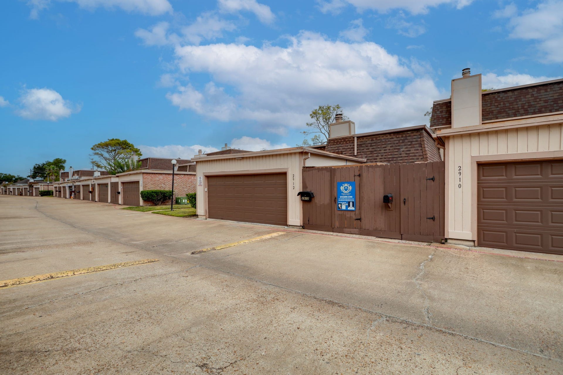 2912 Camelot Lane, Missouri City, TX 77459 A wider view of the paved rear access lane shows the garage approach and surrounding townhomes. Attached garages and gated patio entrances line this side of the community, complementing the landscaped walkways at the front. At 2912 Camelot Lane, the two-car garage rounds out a distinctive single-story investment property.