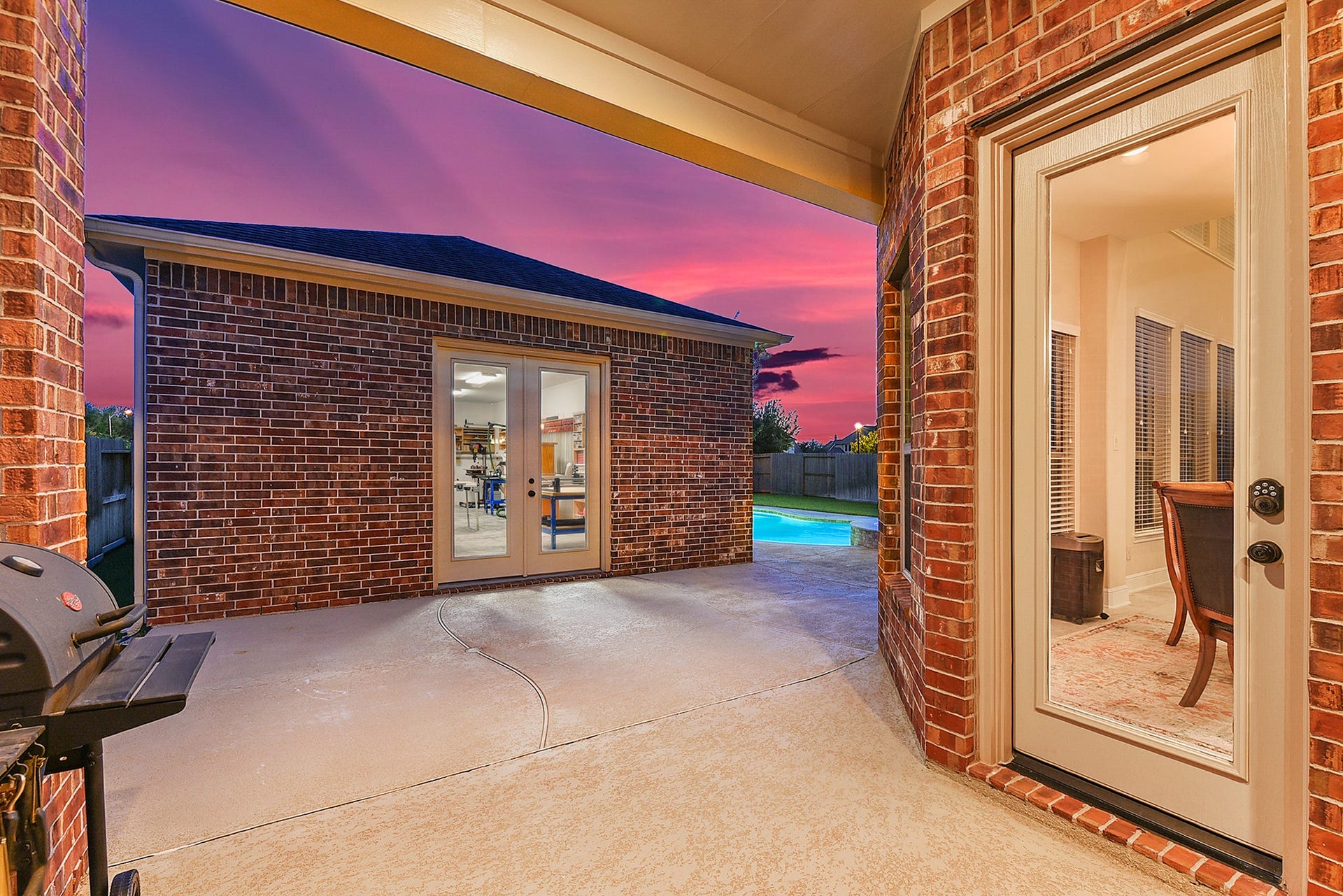 27411 Gladway Manor Drive, Katy, TX 77494 A view from the back door leads to the covered back patio and the impressive additional bonus space, offering approximately 800 square feet of fully air-conditioned and insulated space. Complete with electrical connections and lighting, this versatile area provides endless possibilities for a workshop, hobby space, home office, entertainment area, gym, or additional living space.