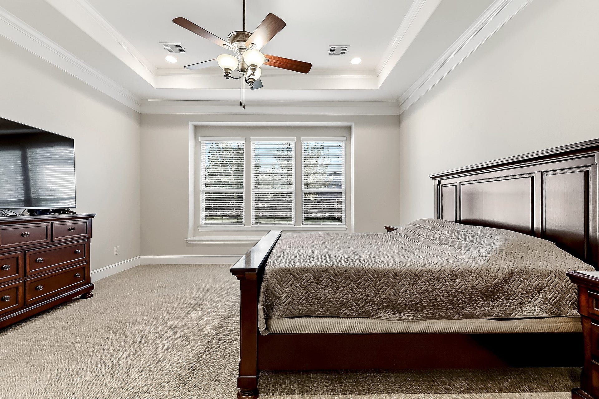 27411 Gladway Manor Drive, Katy, TX 77494 Another view of this spacious owners retreat showcases elegant crown molding, a tray ceiling with a drop-down ceiling fan and recessed lighting, and plush Berber carpet. Large windows provide beautiful views of the backyard, bringing natural light and a peaceful outdoor setting into the room.