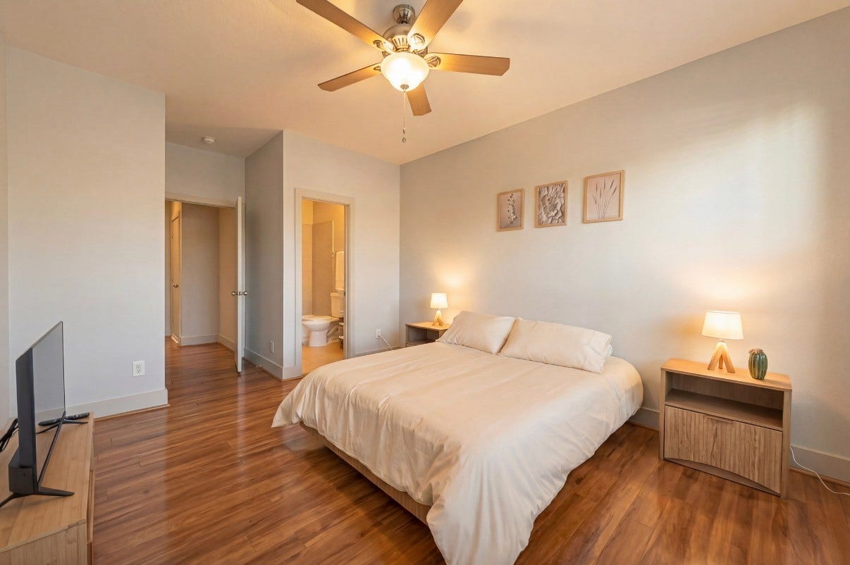 5111 Cornish Street, Houston, TX 77007 Spacious third bedroom on THIRD floor with warm wood flooring, a cozy bed, and soft lighting from bedside lamps, offering a serene and inviting atmosphere.